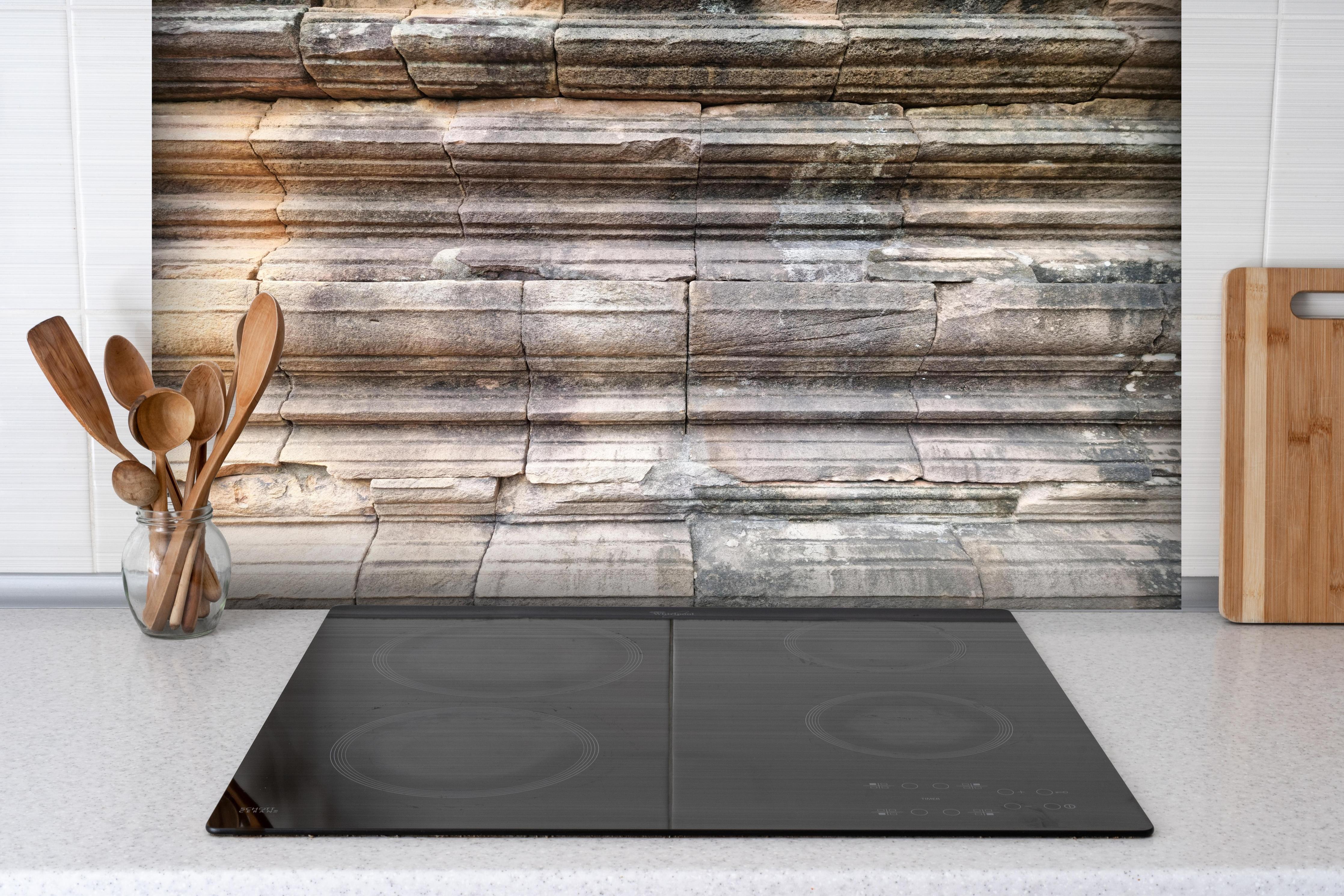 Spritzschutz - Alter Steinziegel - Grunge hinter einem Cerankochfeld zwischen Holz-Kochutensilien