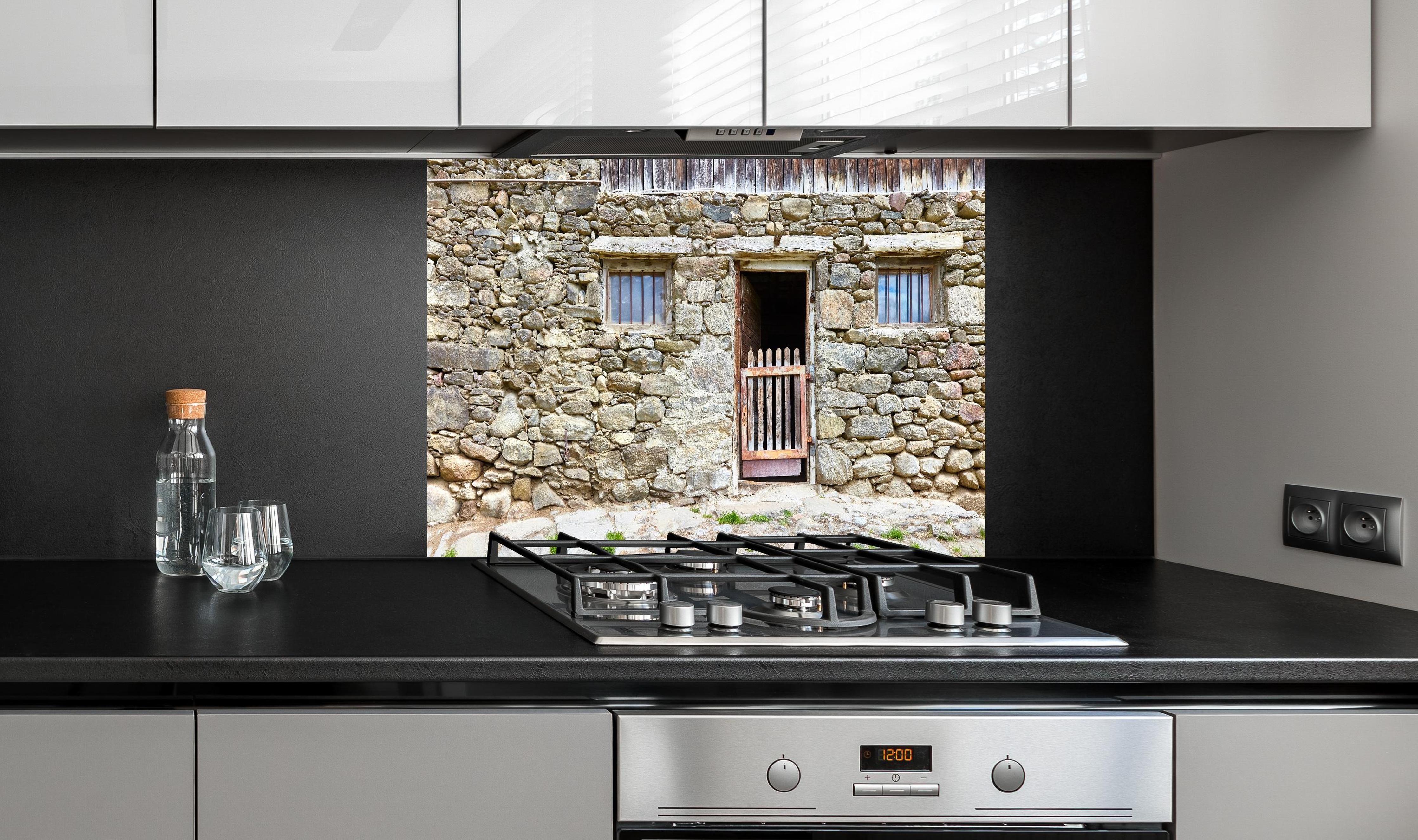 Spritzschutz - Alter Tierstall in Südtirol hinter einem Cerankochfeld zwischen Holz-Kochutensilien