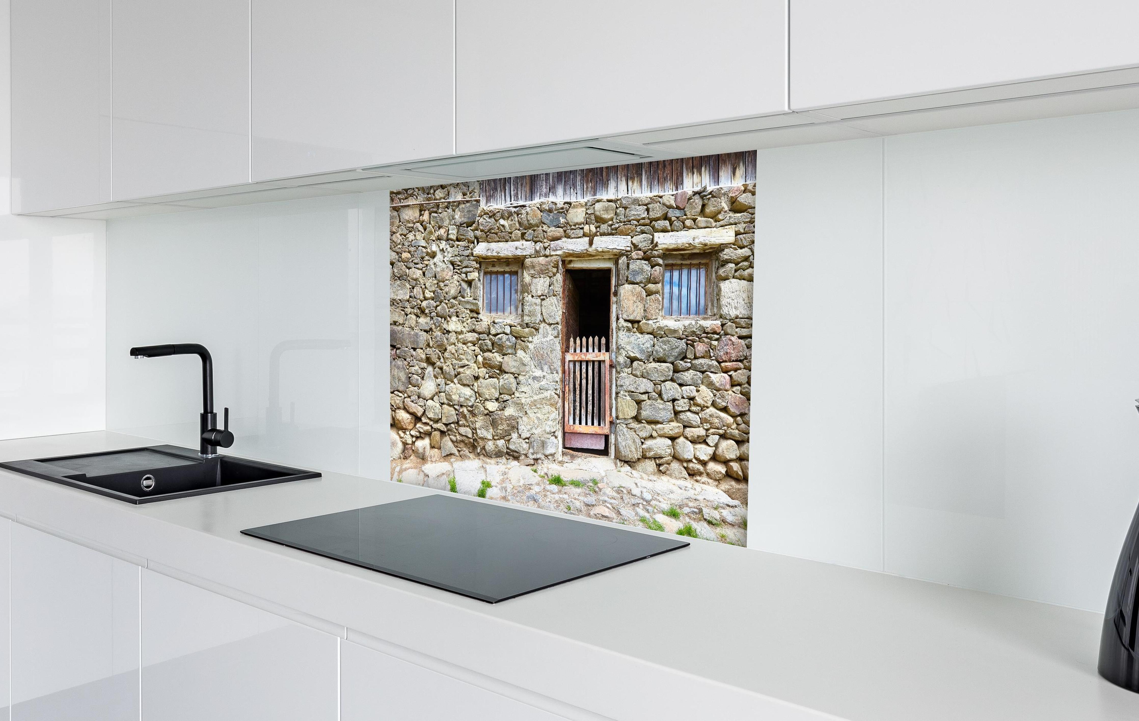 Spritzschutz - Alter Tierstall in Südtirol hinter einem Cerankochfeld zwischen Holz-Kochutensilien