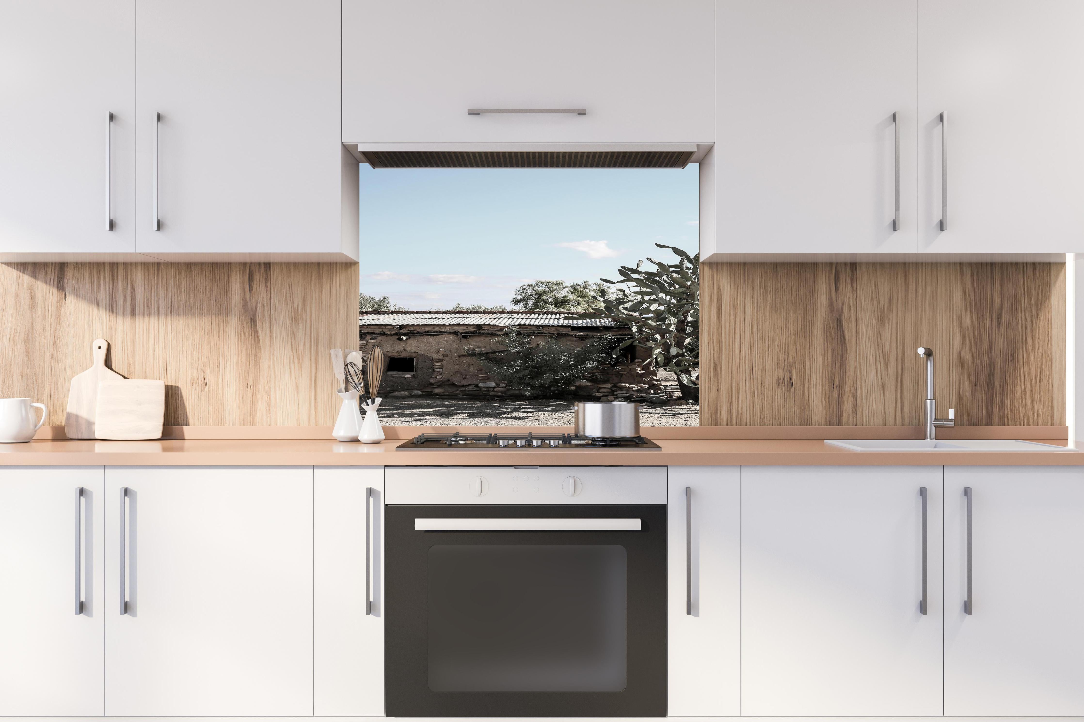 Spritzschutz - Altes Wüstenhaus mit Kakteenschatten hinter einem Cerankochfeld zwischen Holz-Kochutensilien