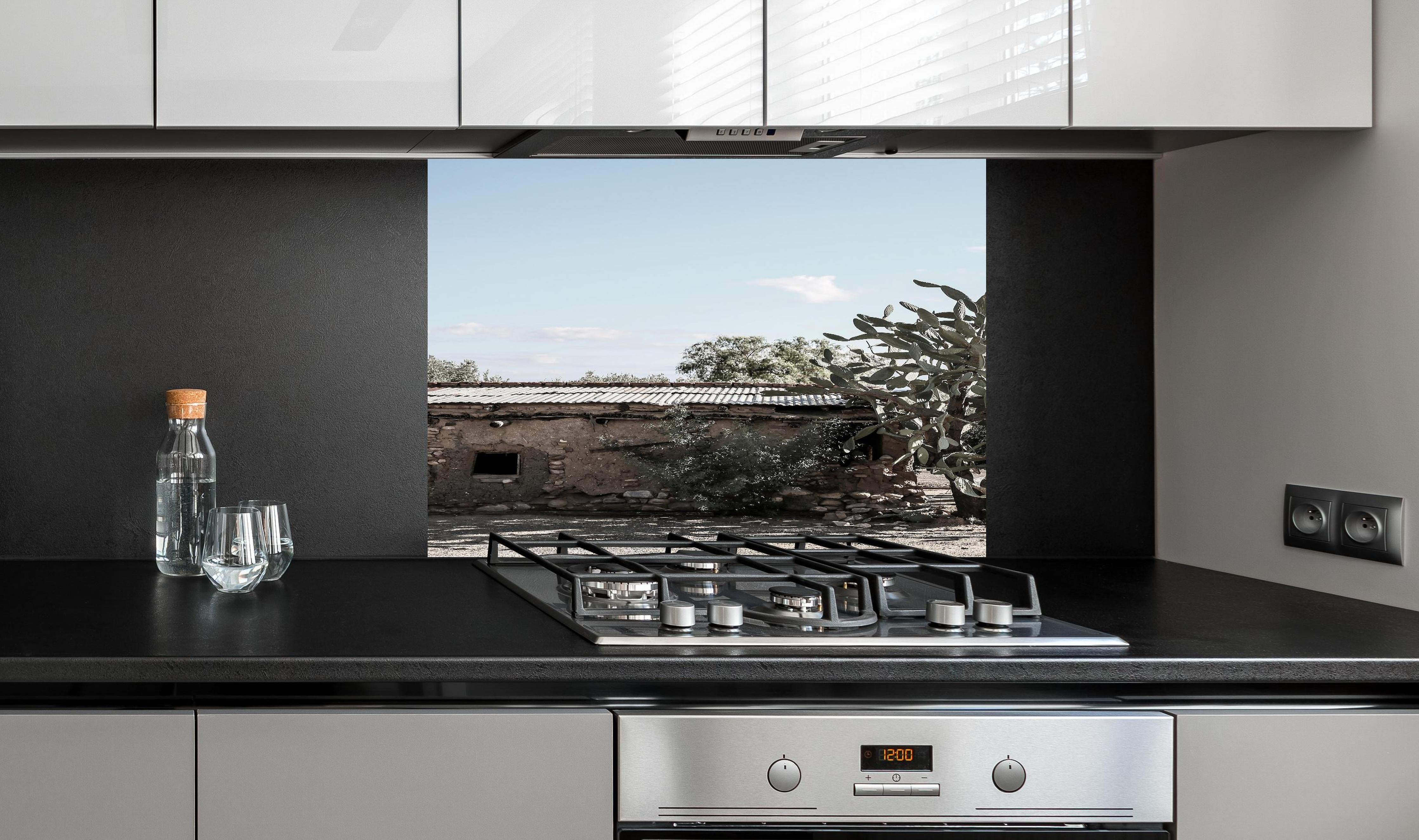 Spritzschutz - Altes Wüstenhaus mit Kakteenschatten hinter einem Cerankochfeld zwischen Holz-Kochutensilien