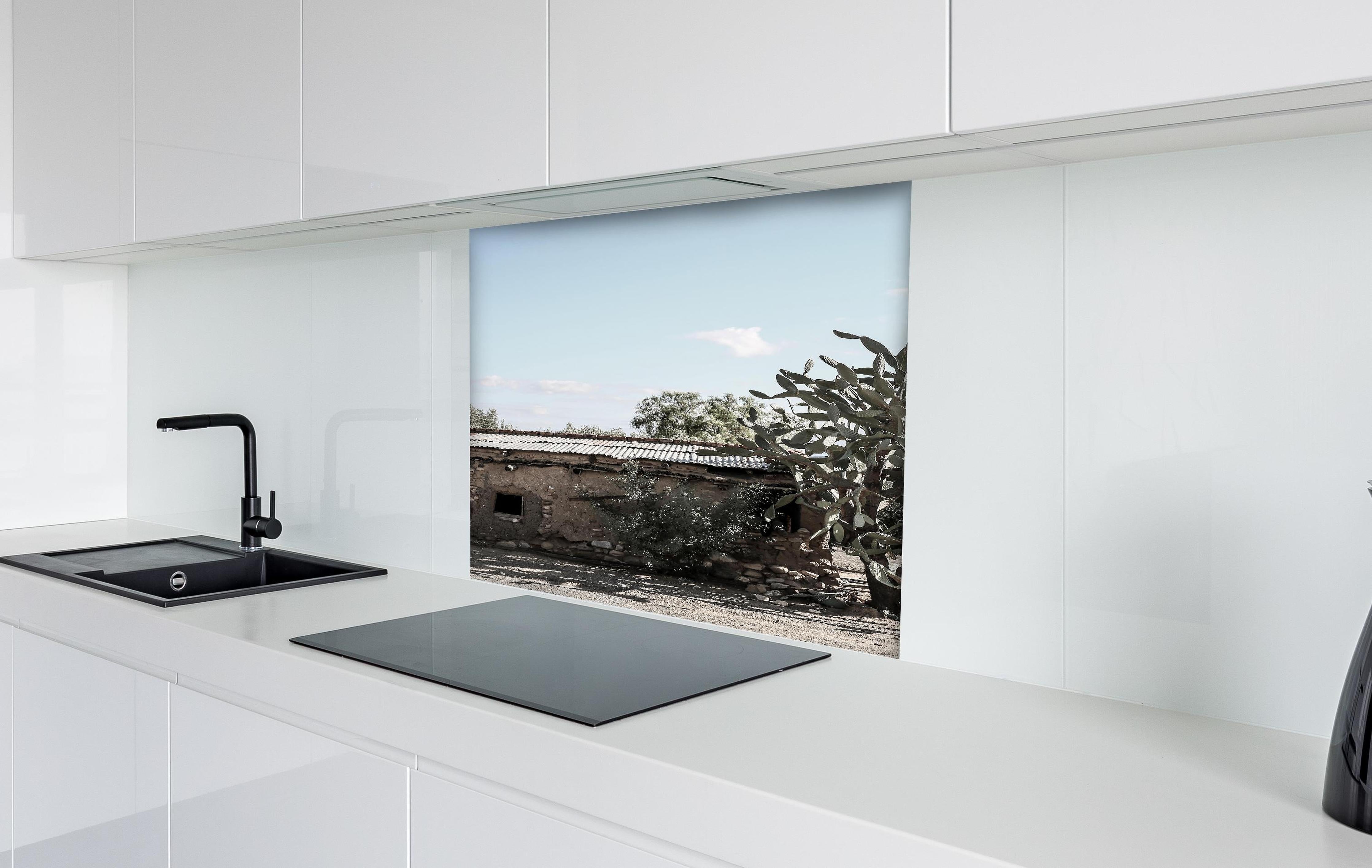 Spritzschutz - Altes Wüstenhaus mit Kakteenschatten hinter einem Cerankochfeld zwischen Holz-Kochutensilien