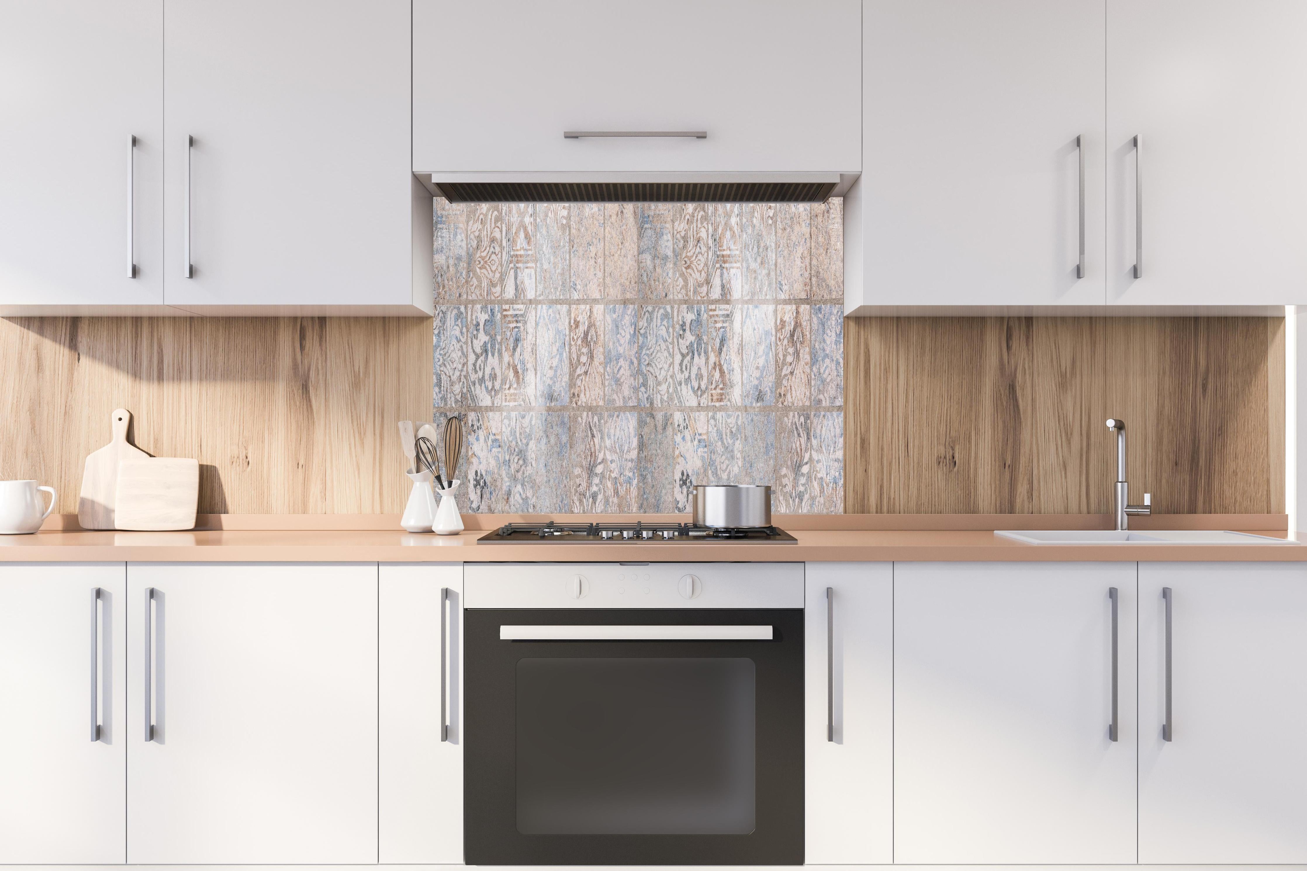 Spritzschutz - Altes blau-braun Patchwork Motiv hinter einem Cerankochfeld zwischen Holz-Kochutensilien