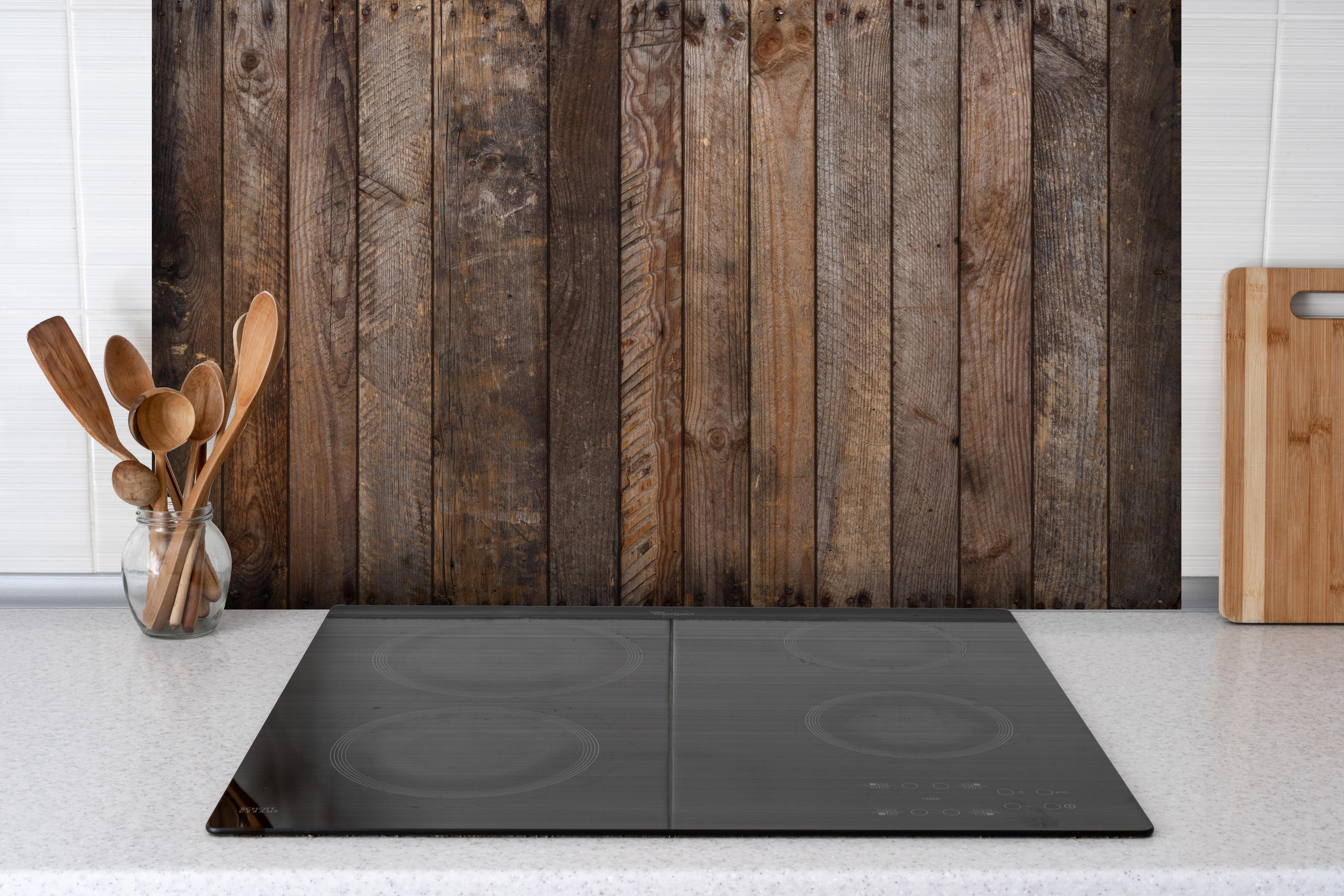 Spritzschutz - Altes verwittertes Plankenholz mit Rostnägeln hinter einem Cerankochfeld zwischen Holz-Kochutensilien