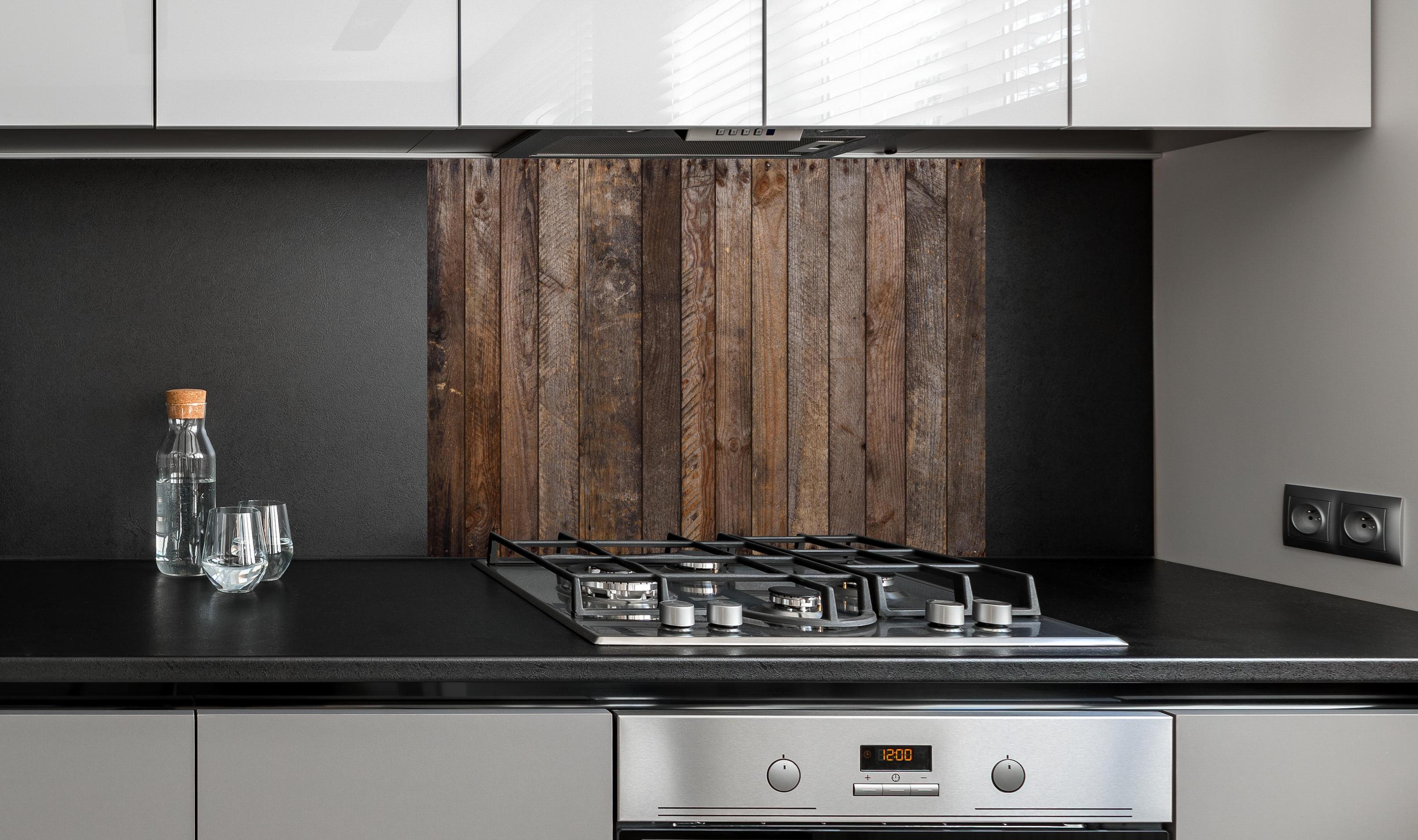 Spritzschutz - Altes verwittertes Plankenholz mit Rostnägeln hinter einem Cerankochfeld zwischen Holz-Kochutensilien