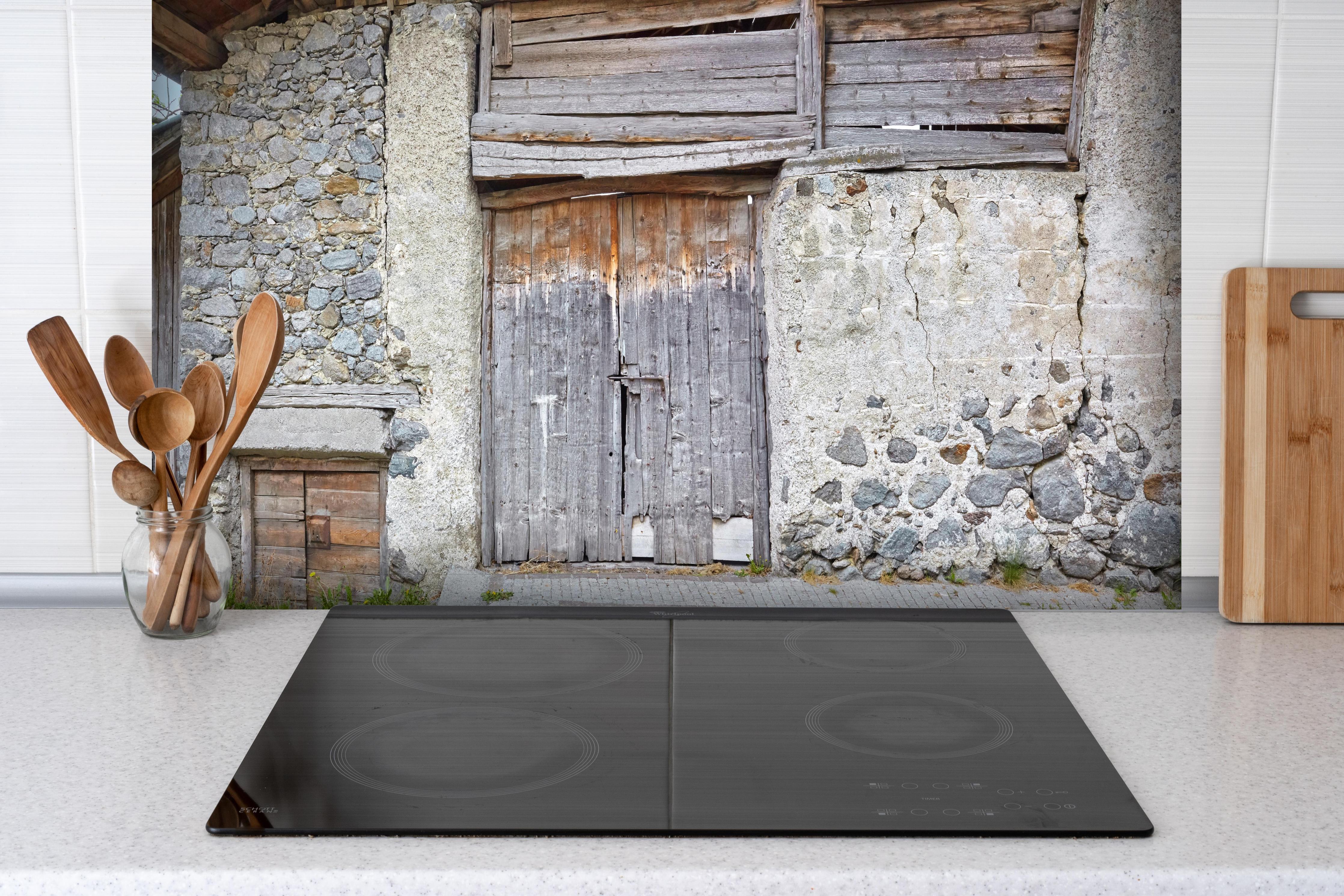 Spritzschutz - Altmodisches Scheunentor, Südtirol hinter einem Cerankochfeld zwischen Holz-Kochutensilien