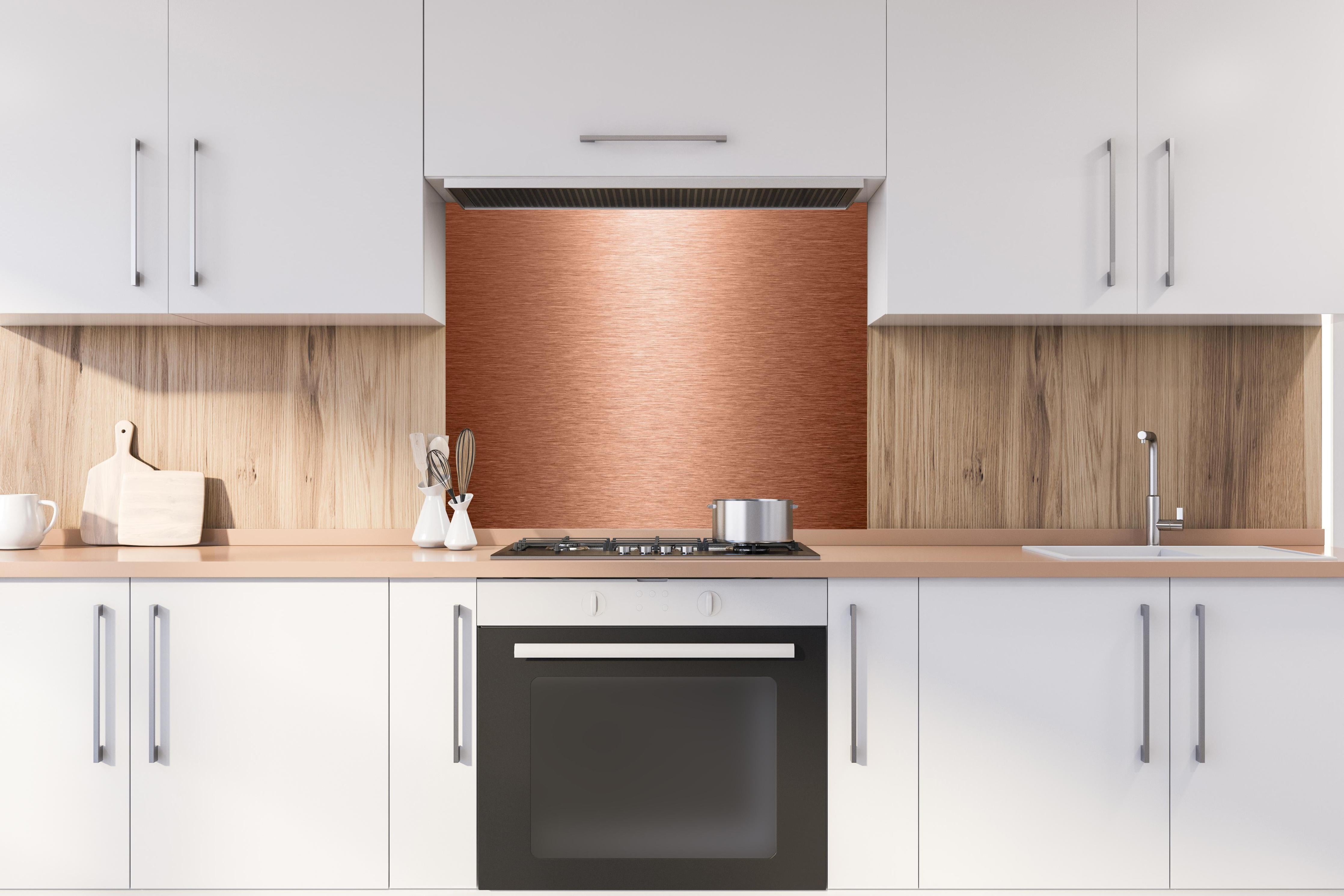 Spritzschutz - Alu gebürstet kupferfarbig hinter einem Cerankochfeld zwischen Holz-Kochutensilien