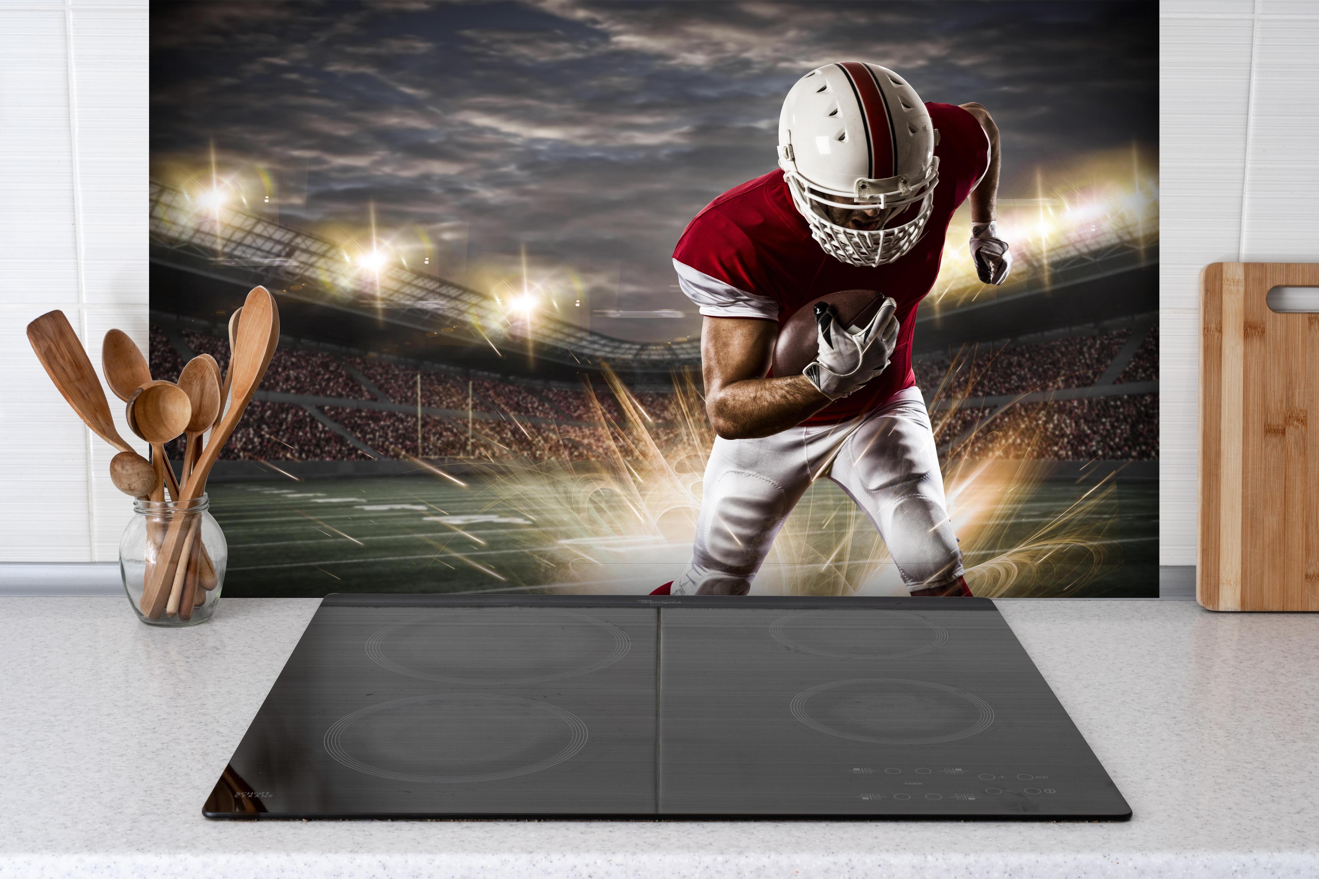 Spritzschutz - American Fußballspieler hinter einem Cerankochfeld zwischen Holz-Kochutensilien