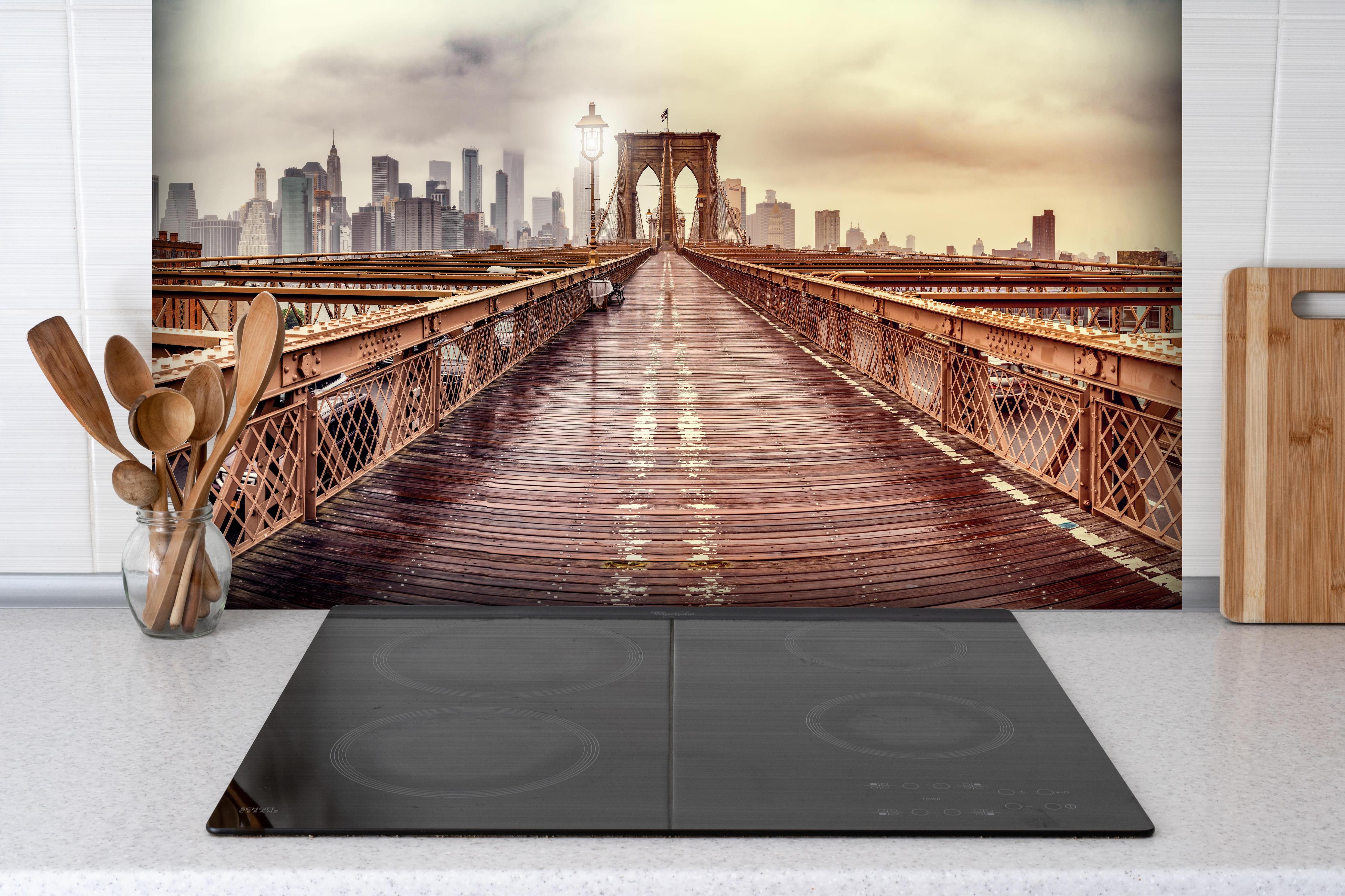 Spritzschutz - Ansicht der Brücke auf die Stadt hinter einem Cerankochfeld zwischen Holz-Kochutensilien