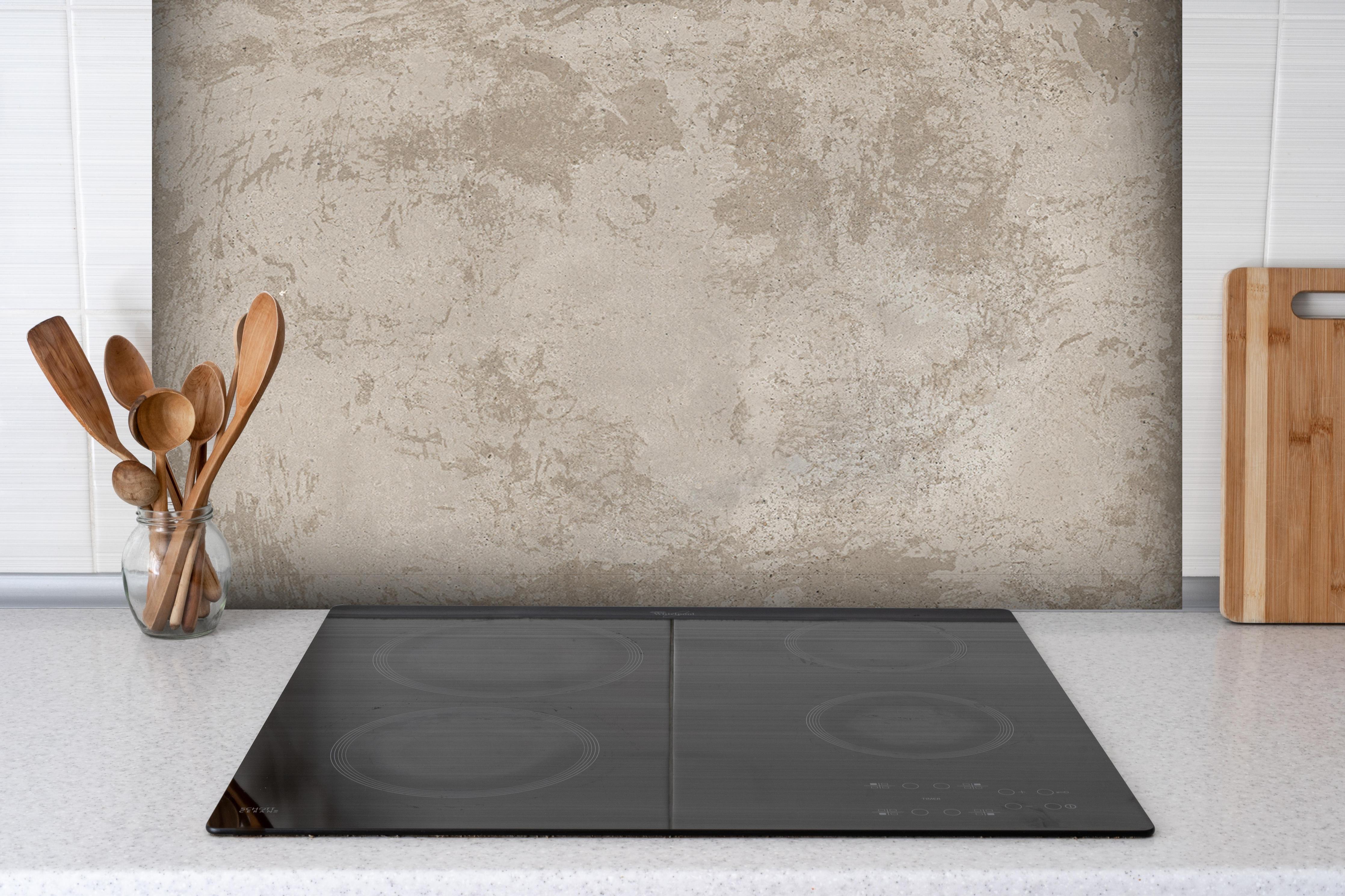 Spritzschutz - Antik beige Betonwand hinter einem Cerankochfeld zwischen Holz-Kochutensilien