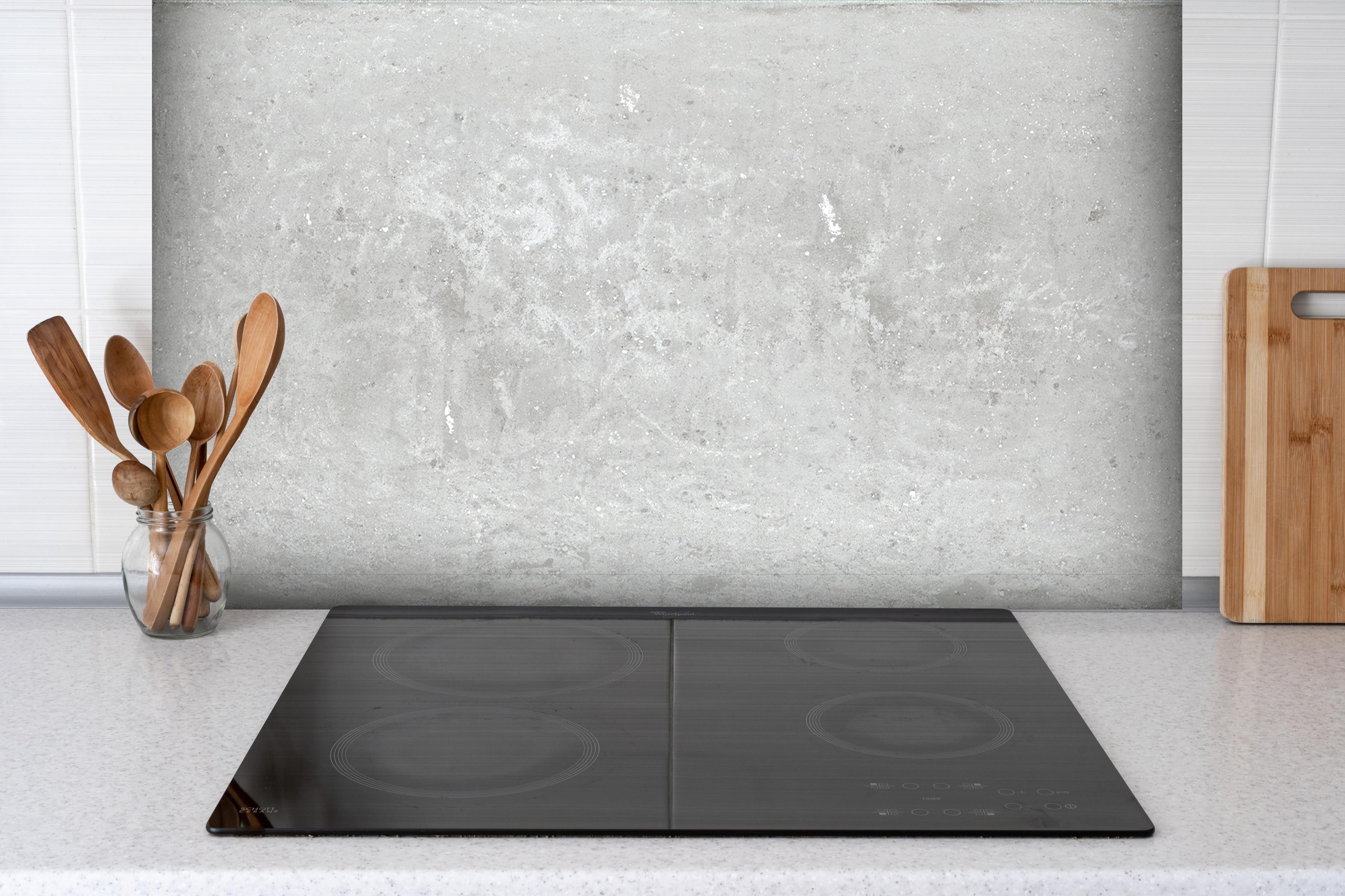 Spritzschutz - Antik weiß-gräuliche Betonwand hinter einem Cerankochfeld zwischen Holz-Kochutensilien