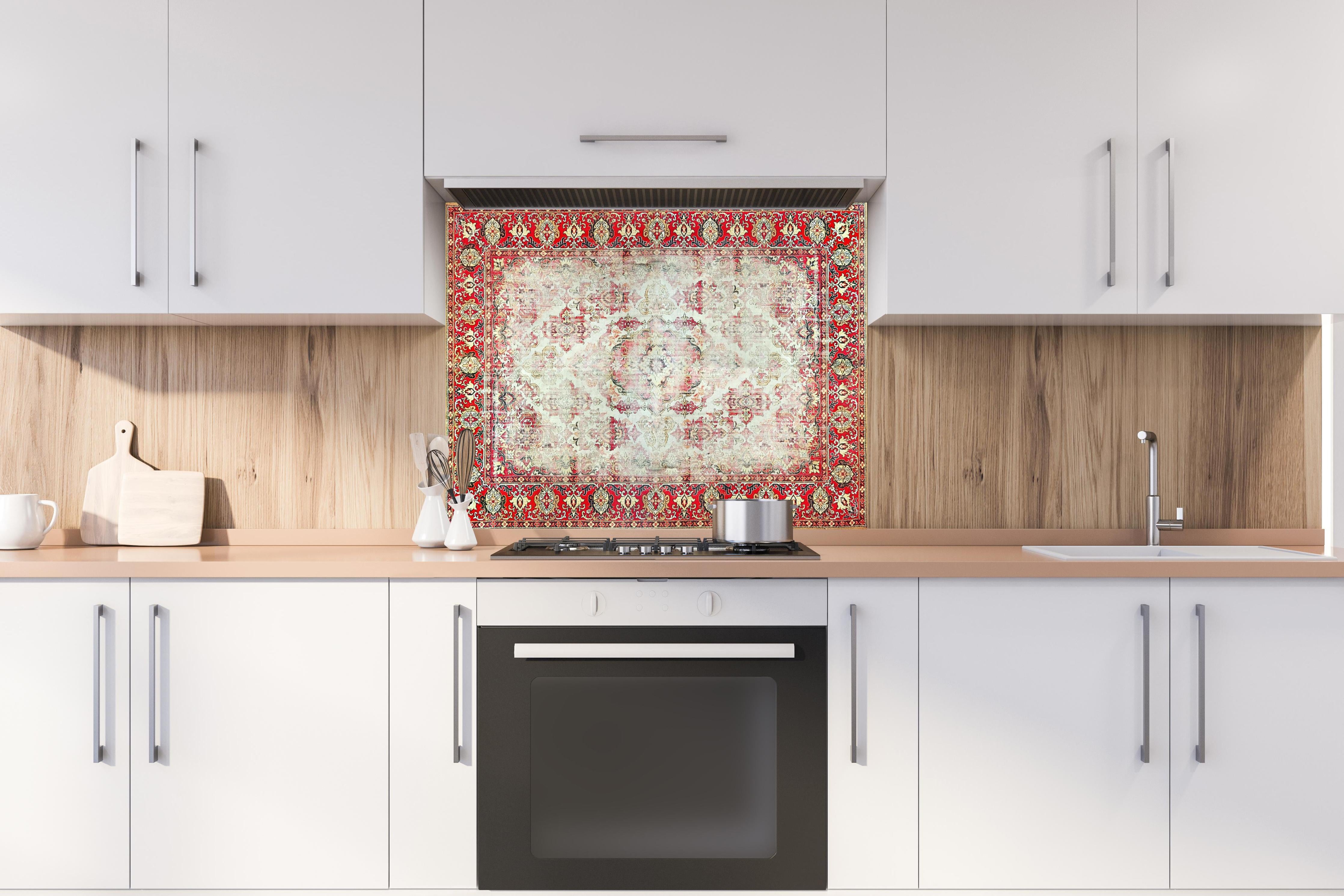 Spritzschutz - Antiker Rot-Beige-Wollteppich mit Muster hinter einem Cerankochfeld zwischen Holz-Kochutensilien