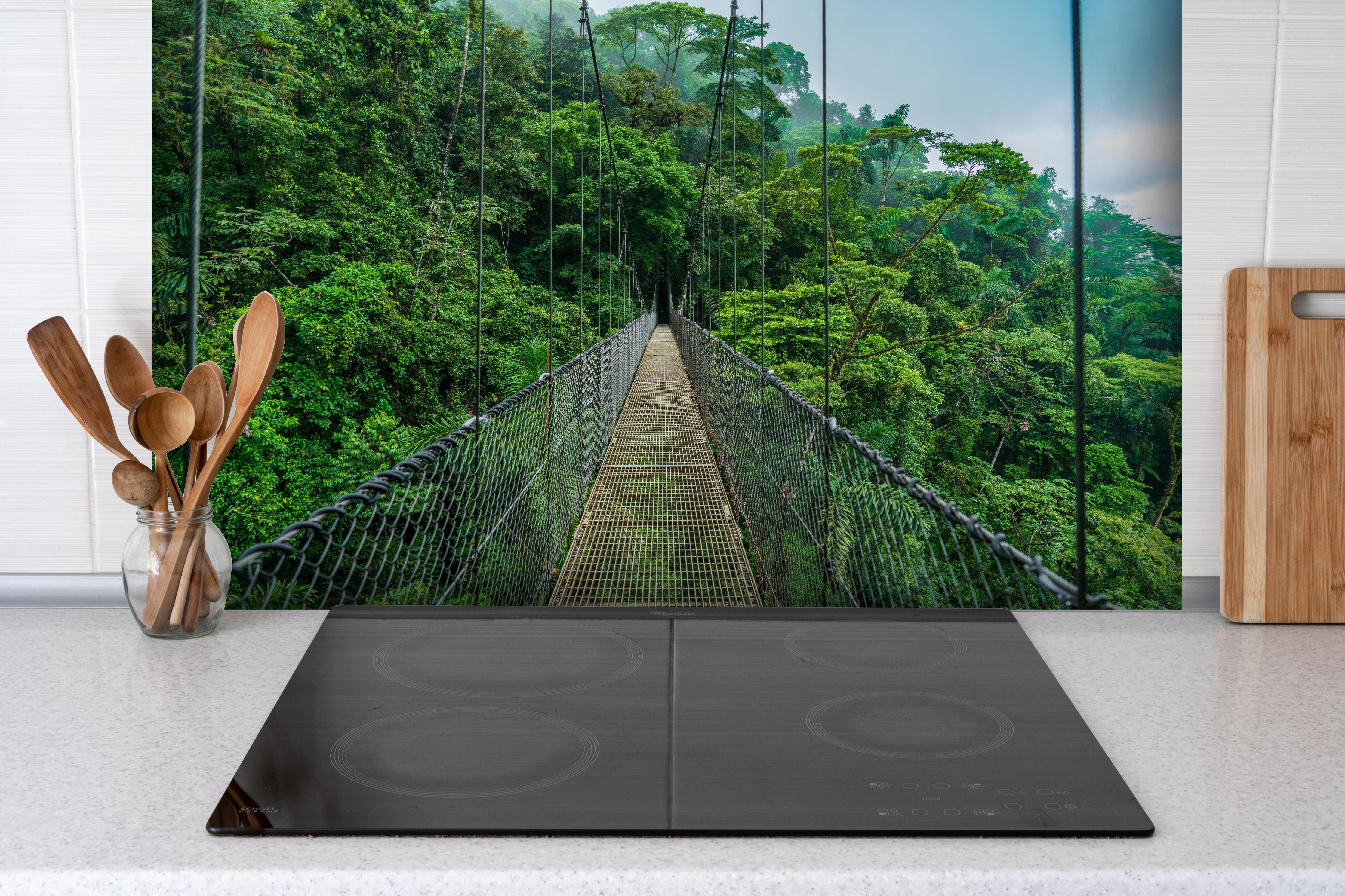 Spritzschutz - Arenal-Hängebrücke - Costa Rica hinter einem Cerankochfeld zwischen Holz-Kochutensilien