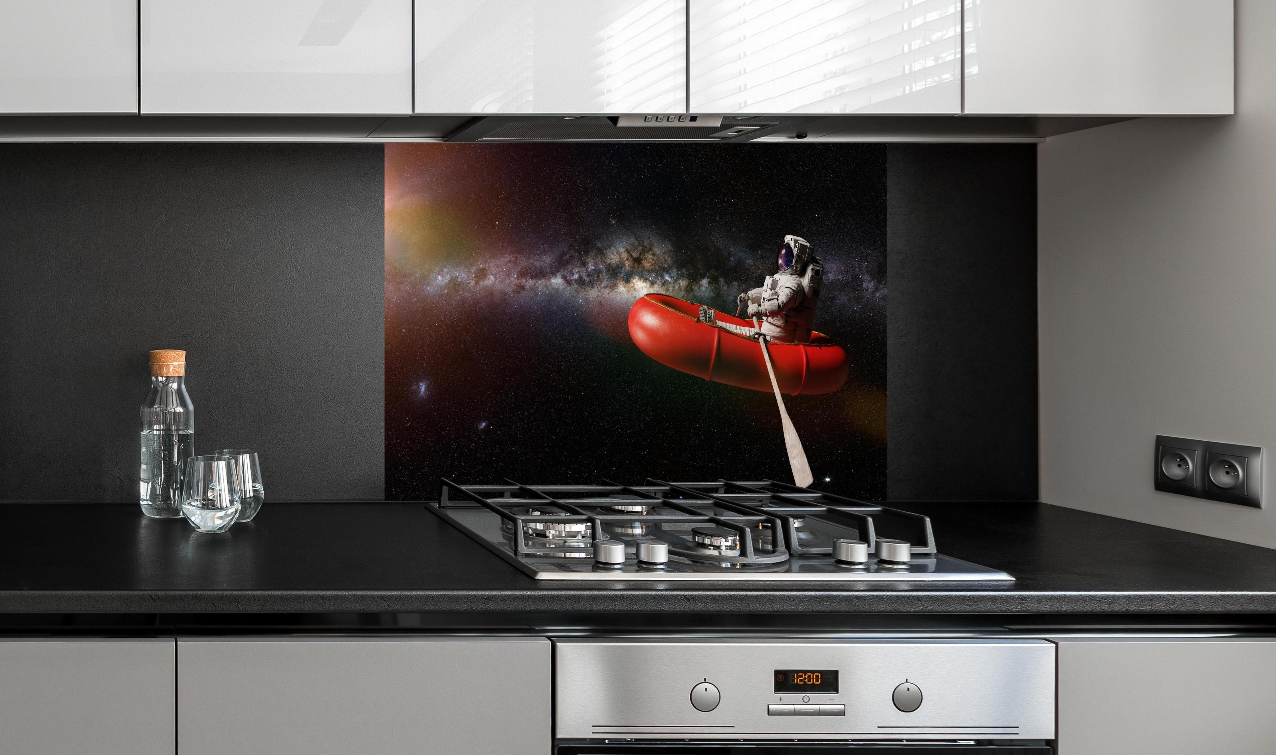 Spritzschutz - Astronaut treibt im Weltall auf Schlauchboot hinter einem Cerankochfeld zwischen Holz-Kochutensilien