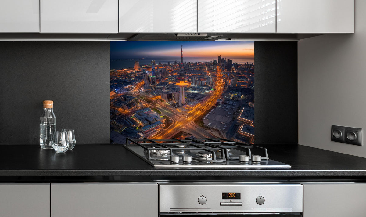 Spritzschutz - Atemberaubendes Abendpanorama Kuwait City hinter einem Cerankochfeld zwischen Holz-Kochutensilien