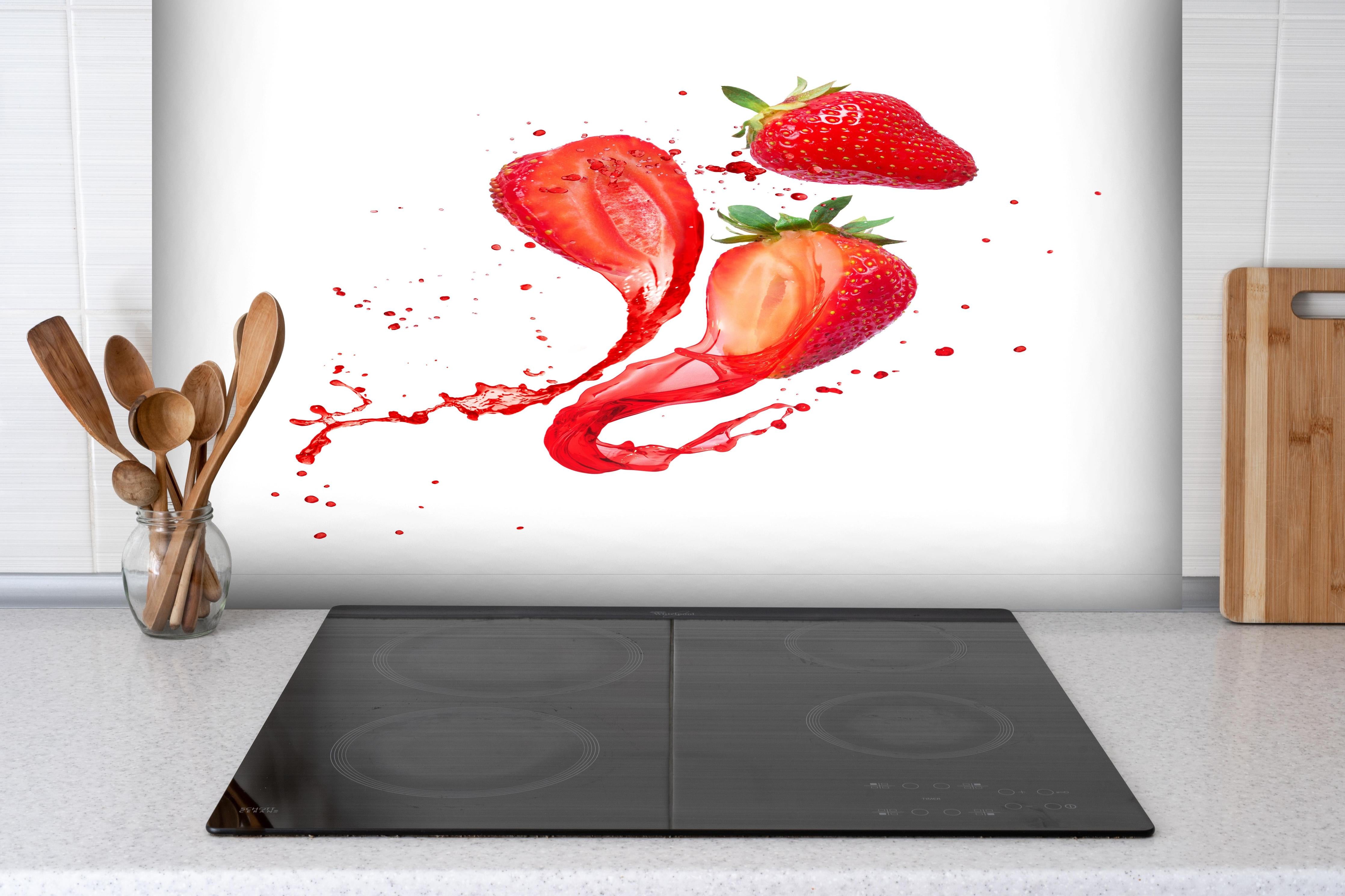 Spritzschutz - Aufgeschnittene Erdbeeren auf weißem Hintergrund hinter einem Cerankochfeld zwischen Holz-Kochutensilien