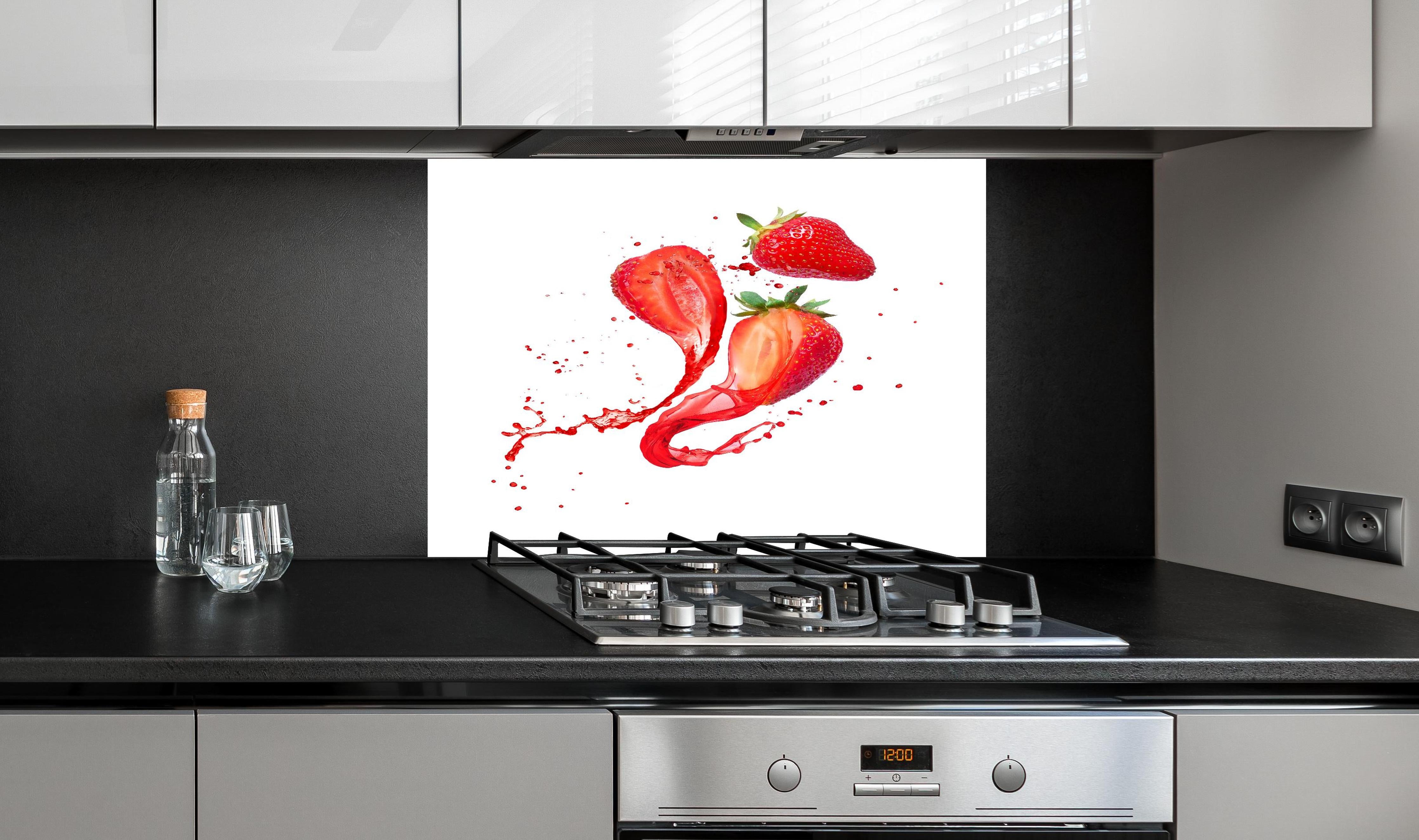 Spritzschutz - Aufgeschnittene Erdbeeren auf weißem Hintergrund hinter einem Cerankochfeld zwischen Holz-Kochutensilien