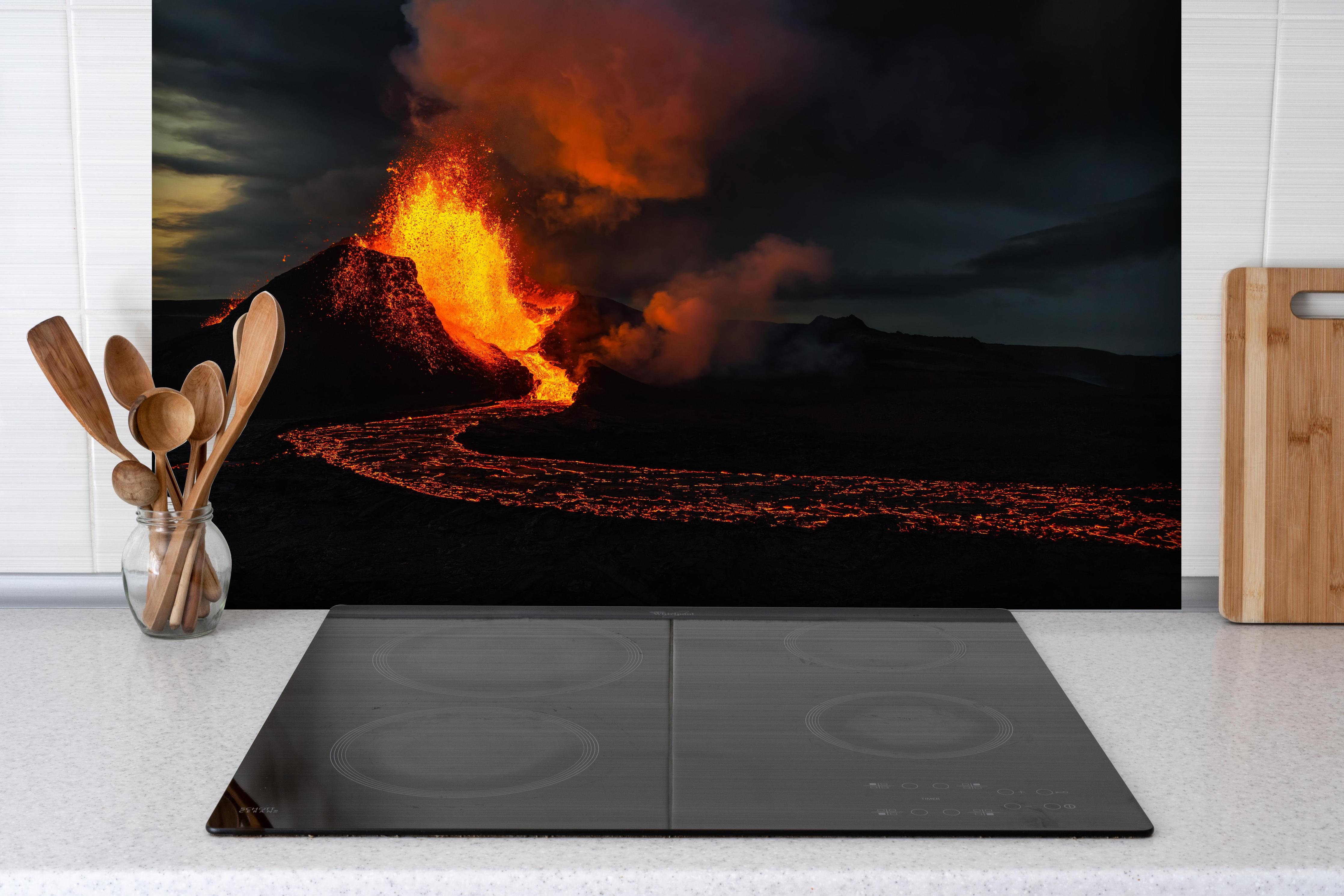 Spritzschutz - Ausbruch vom Vulkan in der Nacht hinter einem Cerankochfeld zwischen Holz-Kochutensilien