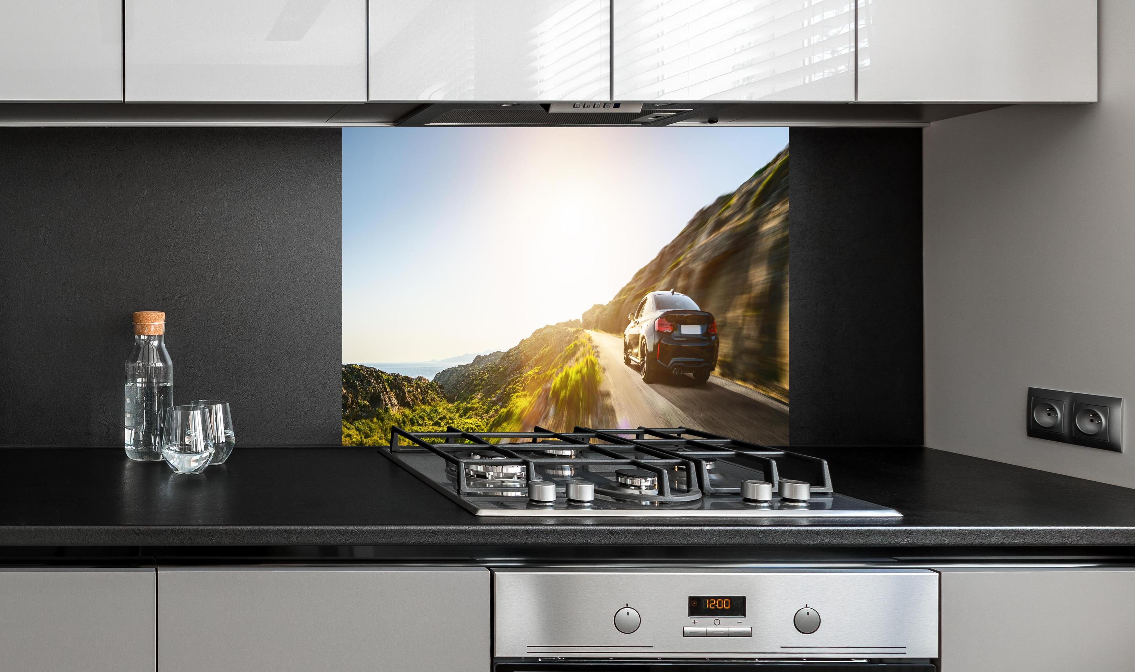 Spritzschutz - Auto fährt über eine Straße auf Bergen hinter einem Cerankochfeld zwischen Holz-Kochutensilien