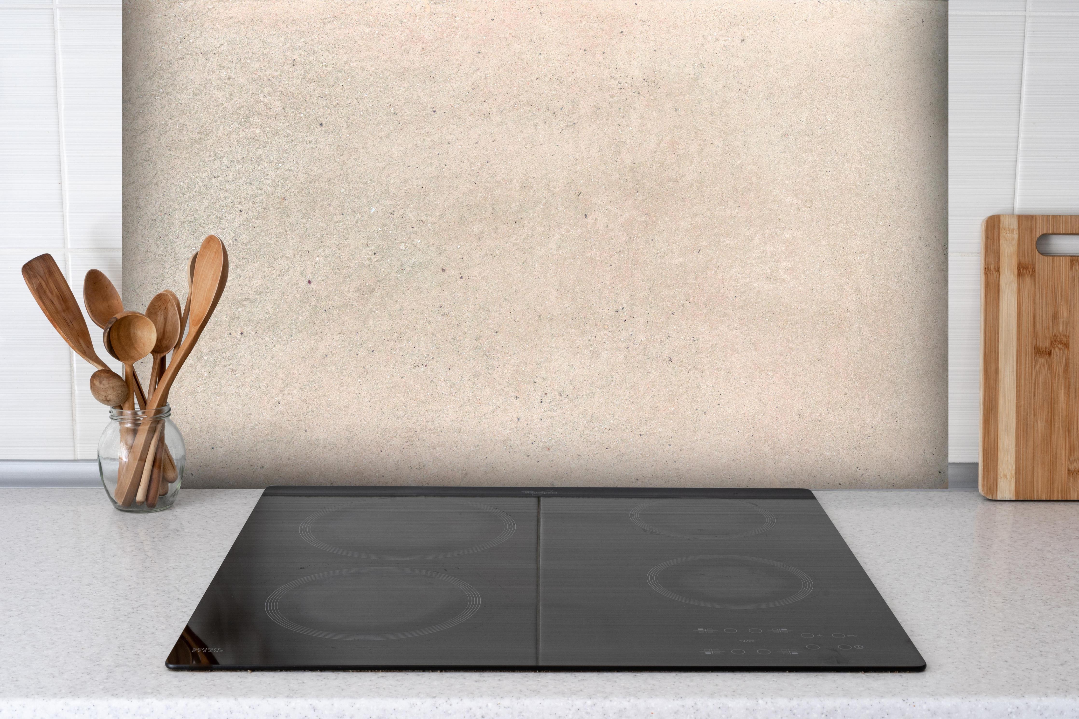 Spritzschutz - Beige Betonhintergrund hinter einem Cerankochfeld zwischen Holz-Kochutensilien