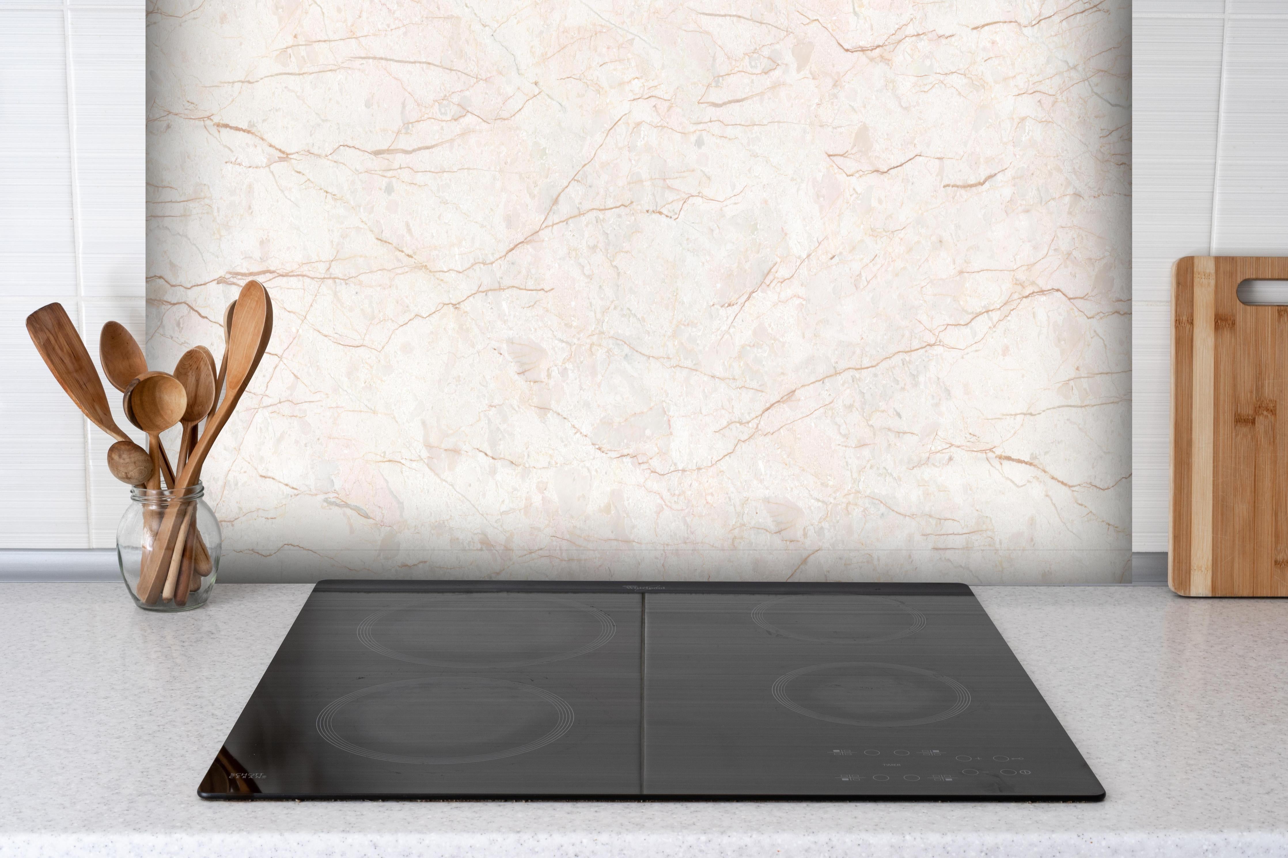 Spritzschutz - Beige Marmor Hintergrund hinter einem Cerankochfeld zwischen Holz-Kochutensilien