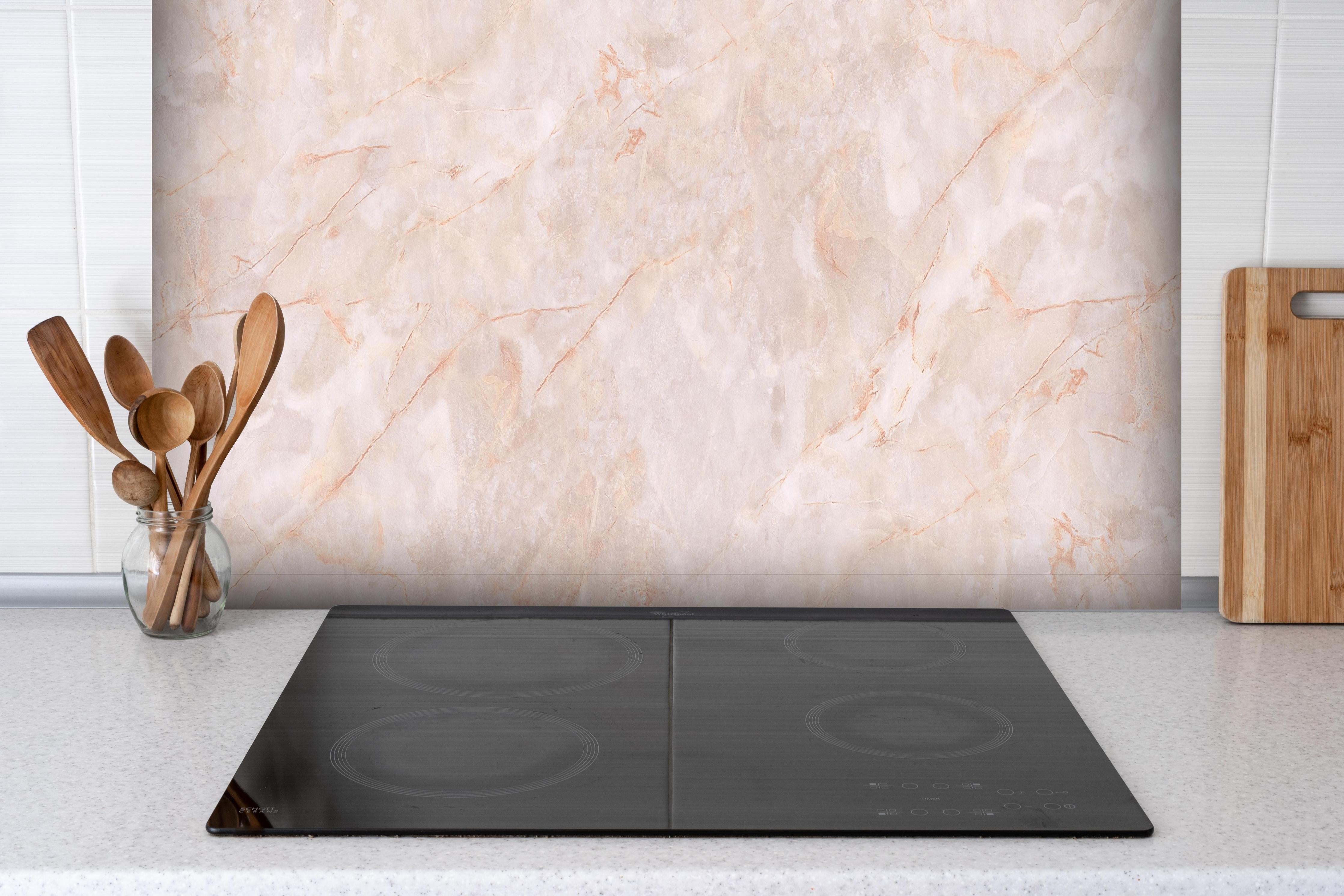 Spritzschutz - Beige-Rosa Marmorstein hinter einem Cerankochfeld zwischen Holz-Kochutensilien