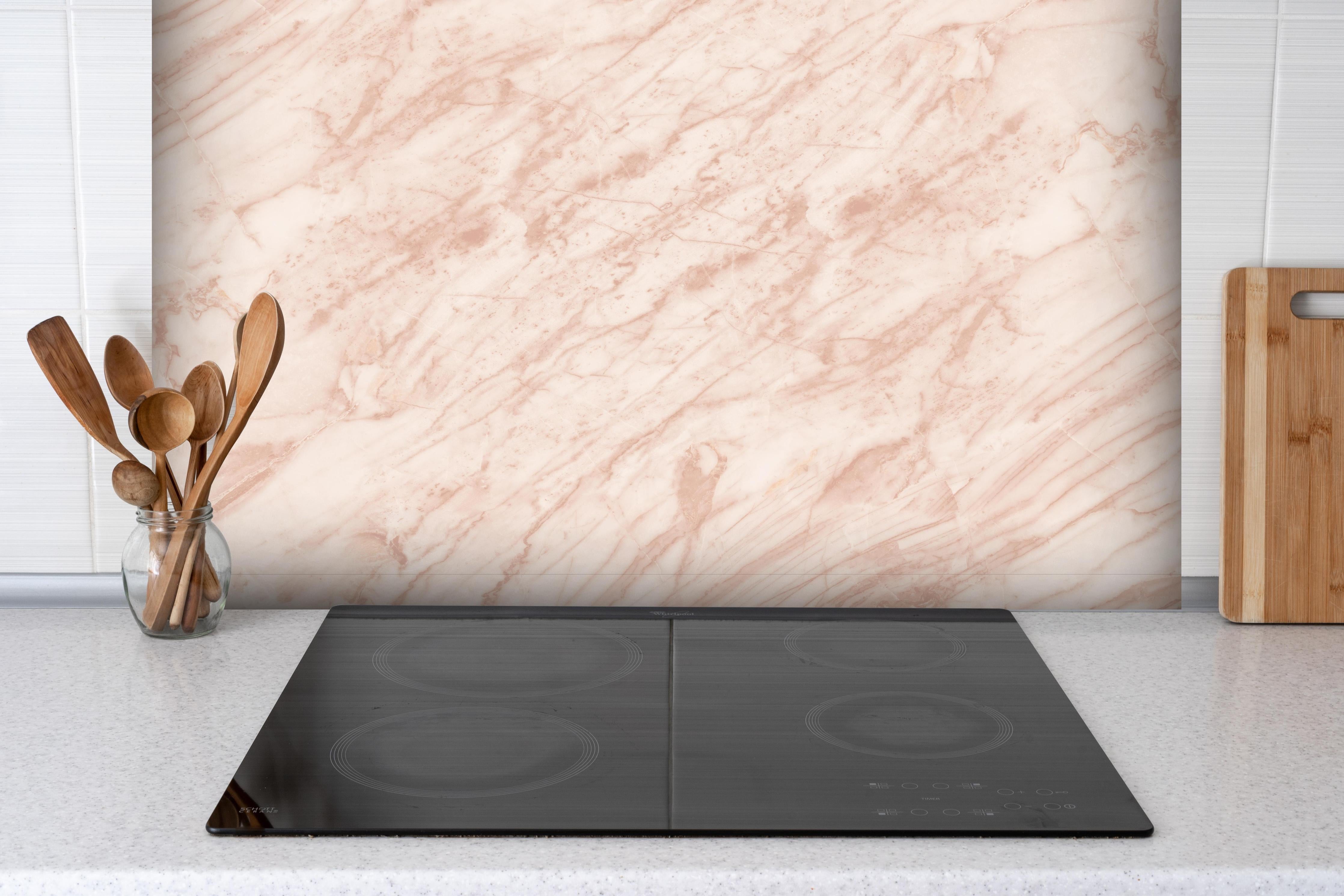 Spritzschutz - Beiger abstrakter Marmor hinter einem Cerankochfeld zwischen Holz-Kochutensilien