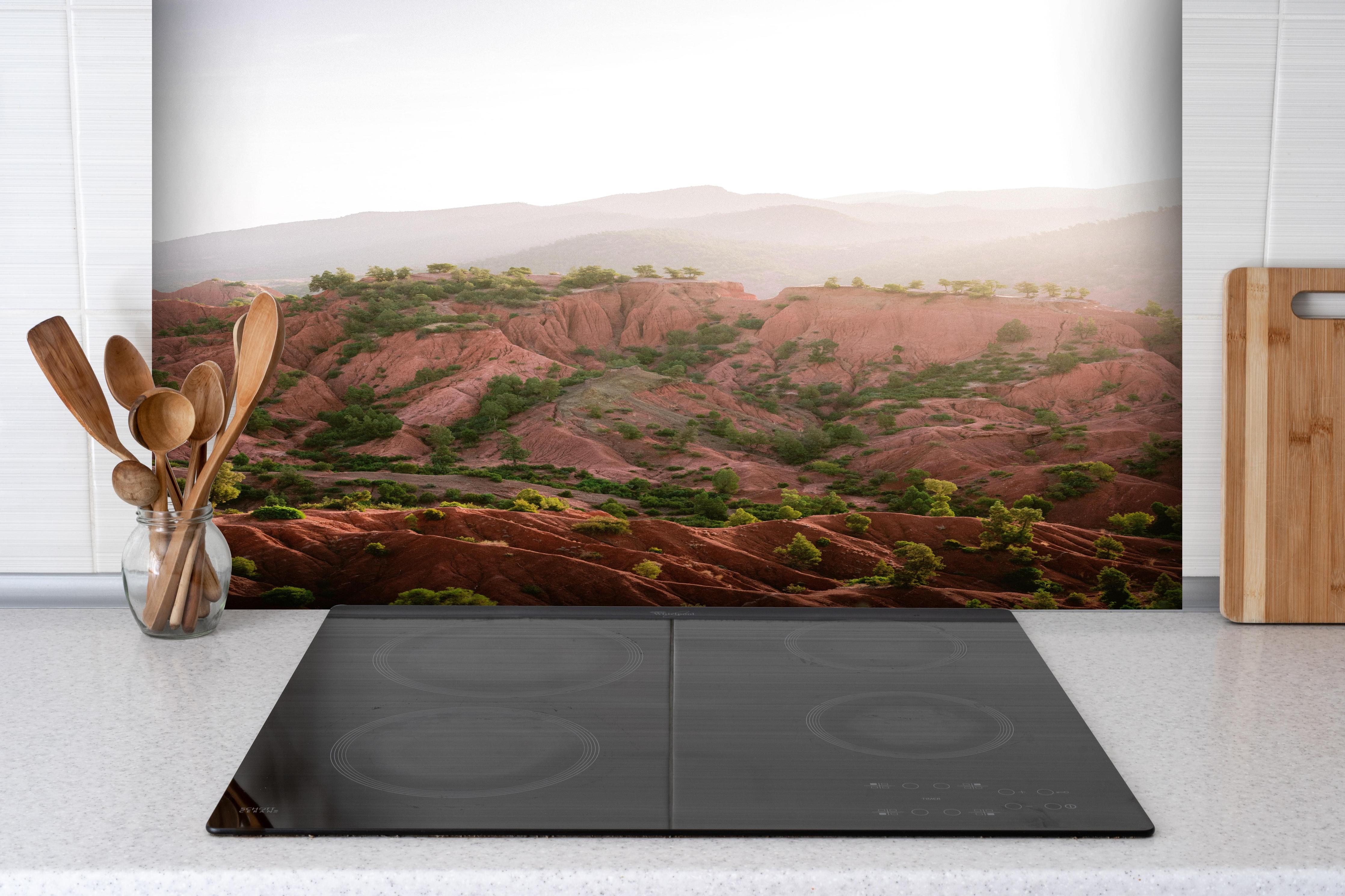 Spritzschutz - Berglandschaft im Ourika-Tal bei Sonnenaufgang hinter einem Cerankochfeld zwischen Holz-Kochutensilien