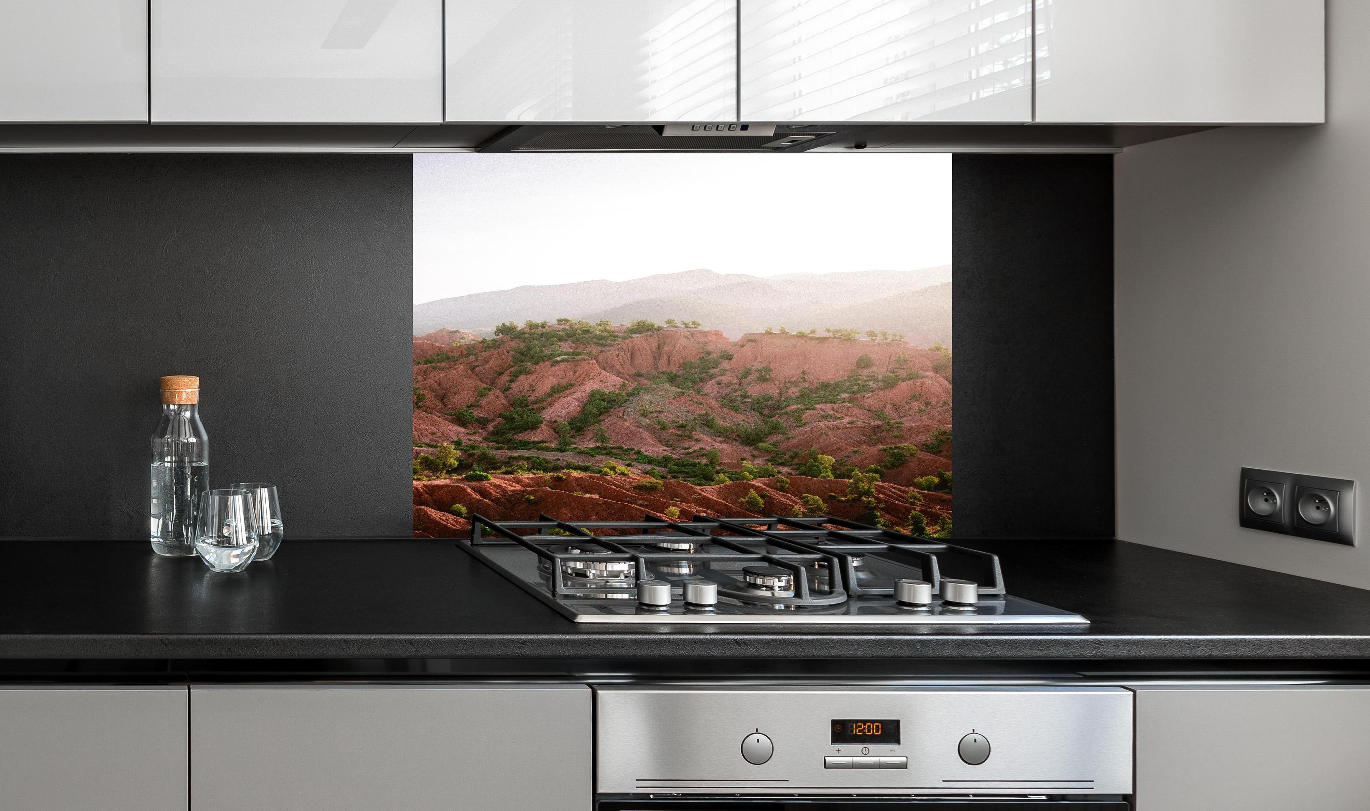 Spritzschutz - Berglandschaft im Ourika-Tal bei Sonnenaufgang hinter einem Cerankochfeld zwischen Holz-Kochutensilien