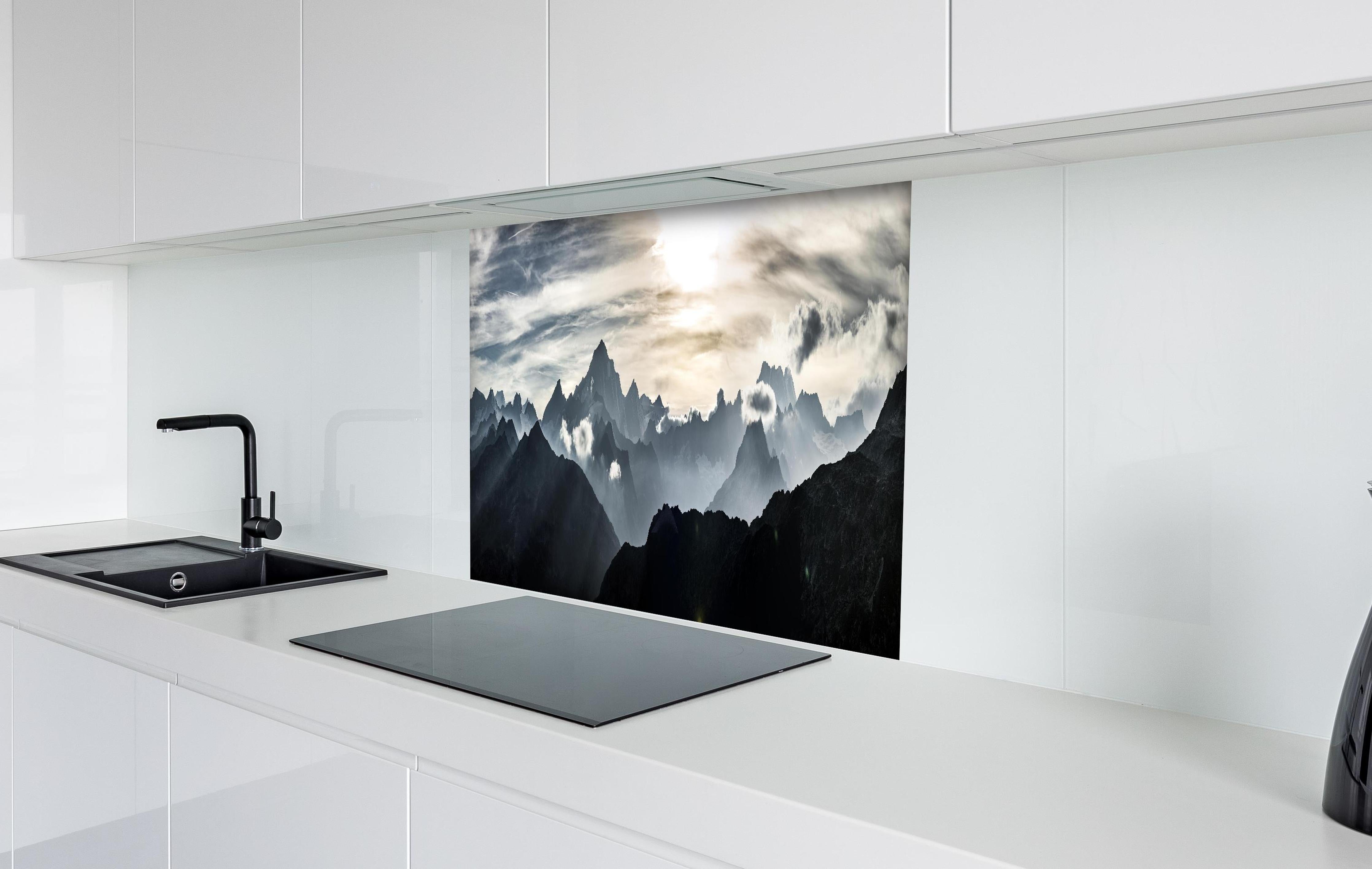 Spritzschutz - Bergpanorama mit Sonnenuntergangslicht hinter einem Cerankochfeld zwischen Holz-Kochutensilien