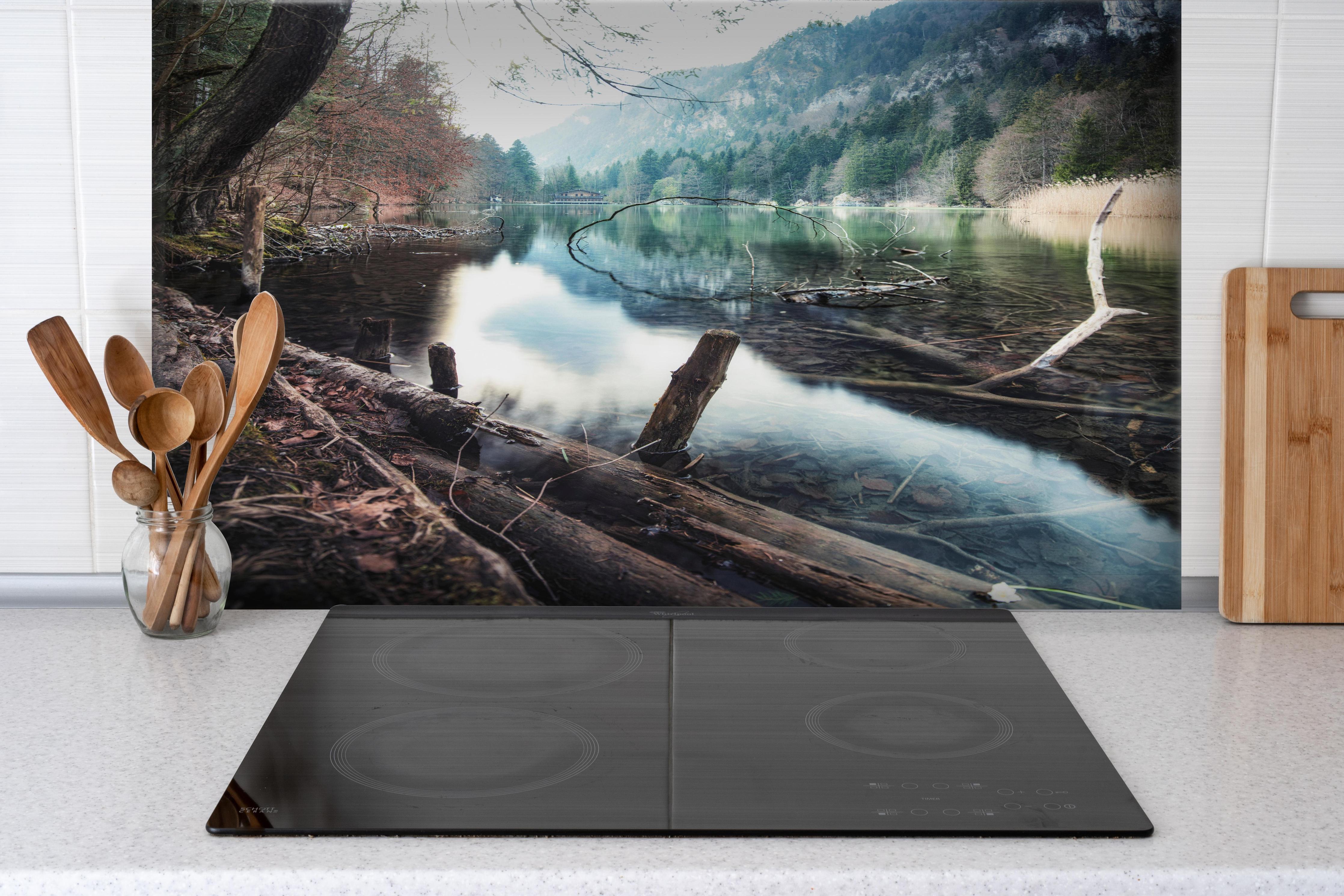 Spritzschutz - Bergsee im Kaskada Wald hinter einem Cerankochfeld zwischen Holz-Kochutensilien