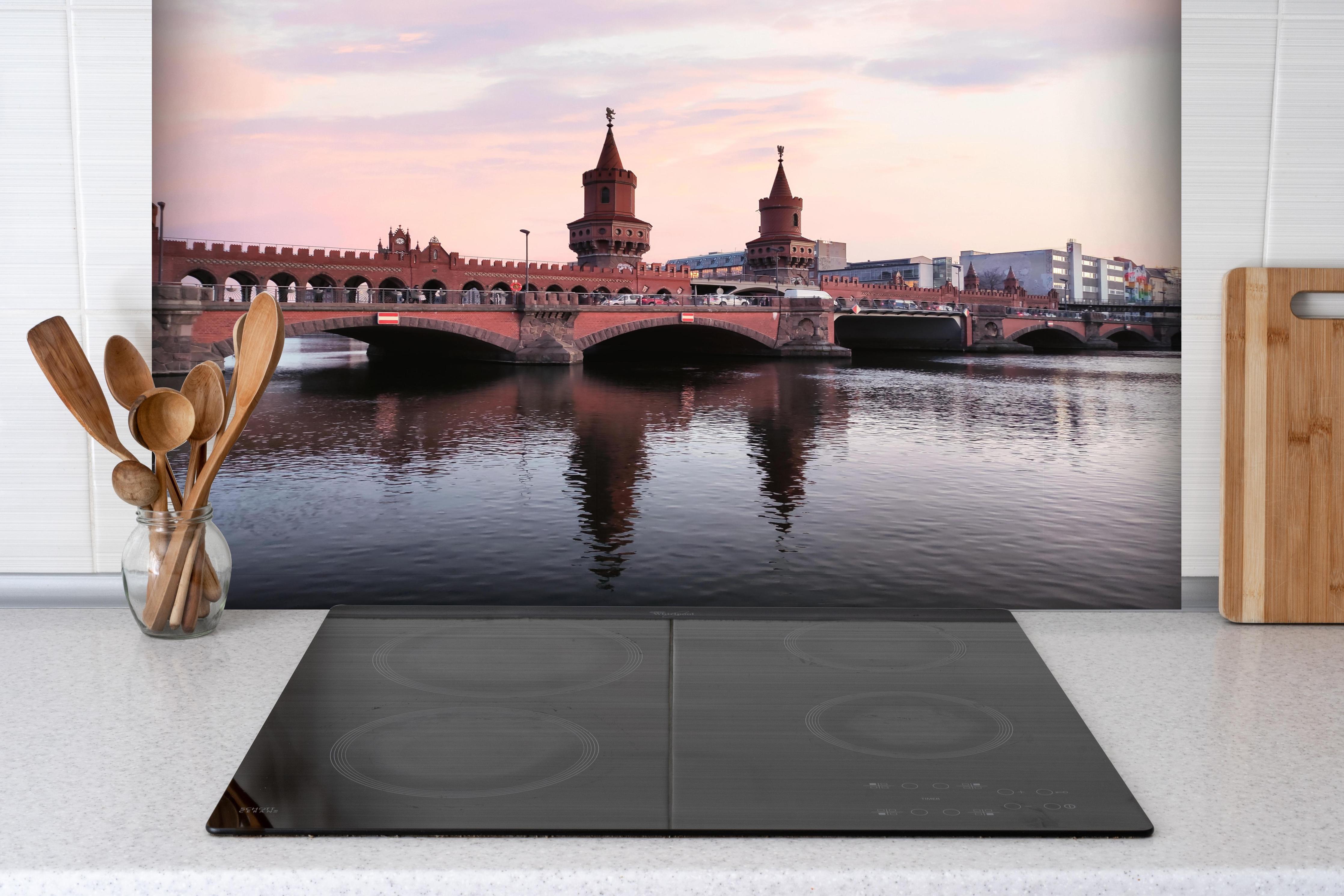 Spritzschutz - Berliner Brücke bei Tag hinter einem Cerankochfeld zwischen Holz-Kochutensilien