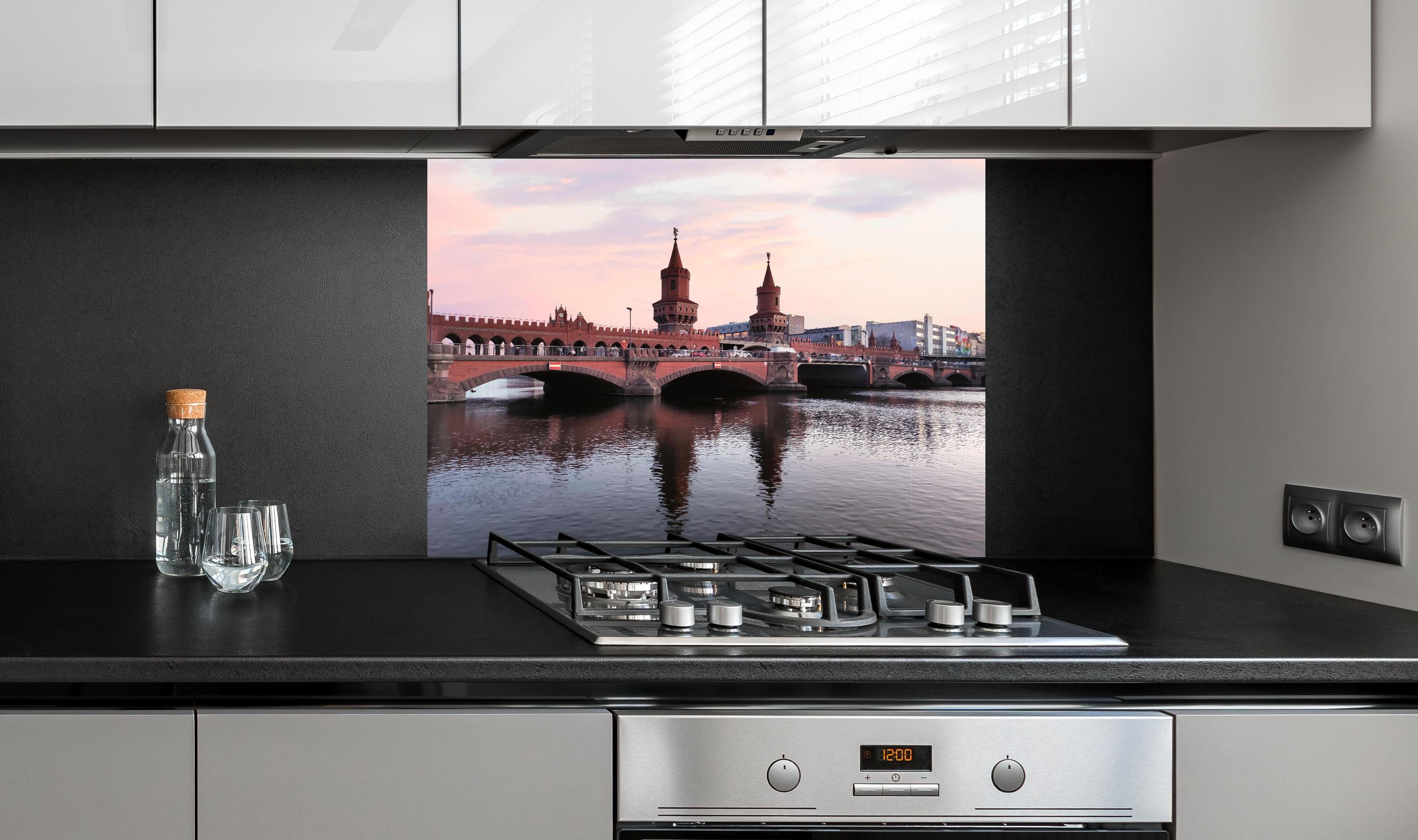 Spritzschutz - Berliner Brücke bei Tag hinter einem Cerankochfeld zwischen Holz-Kochutensilien