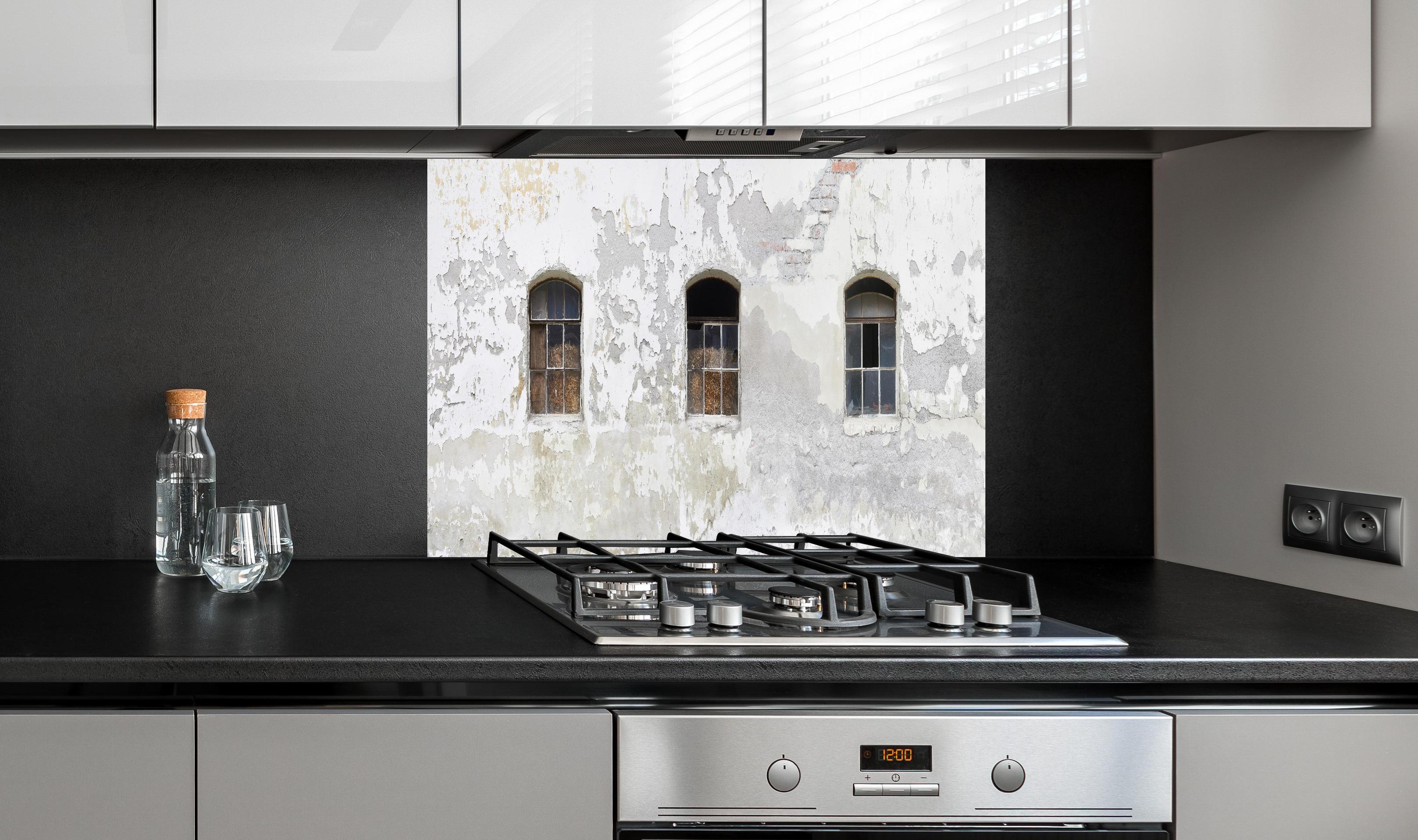 Spritzschutz - Beschädigte Fenster einer veralteten Hauswand hinter einem Cerankochfeld zwischen Holz-Kochutensilien