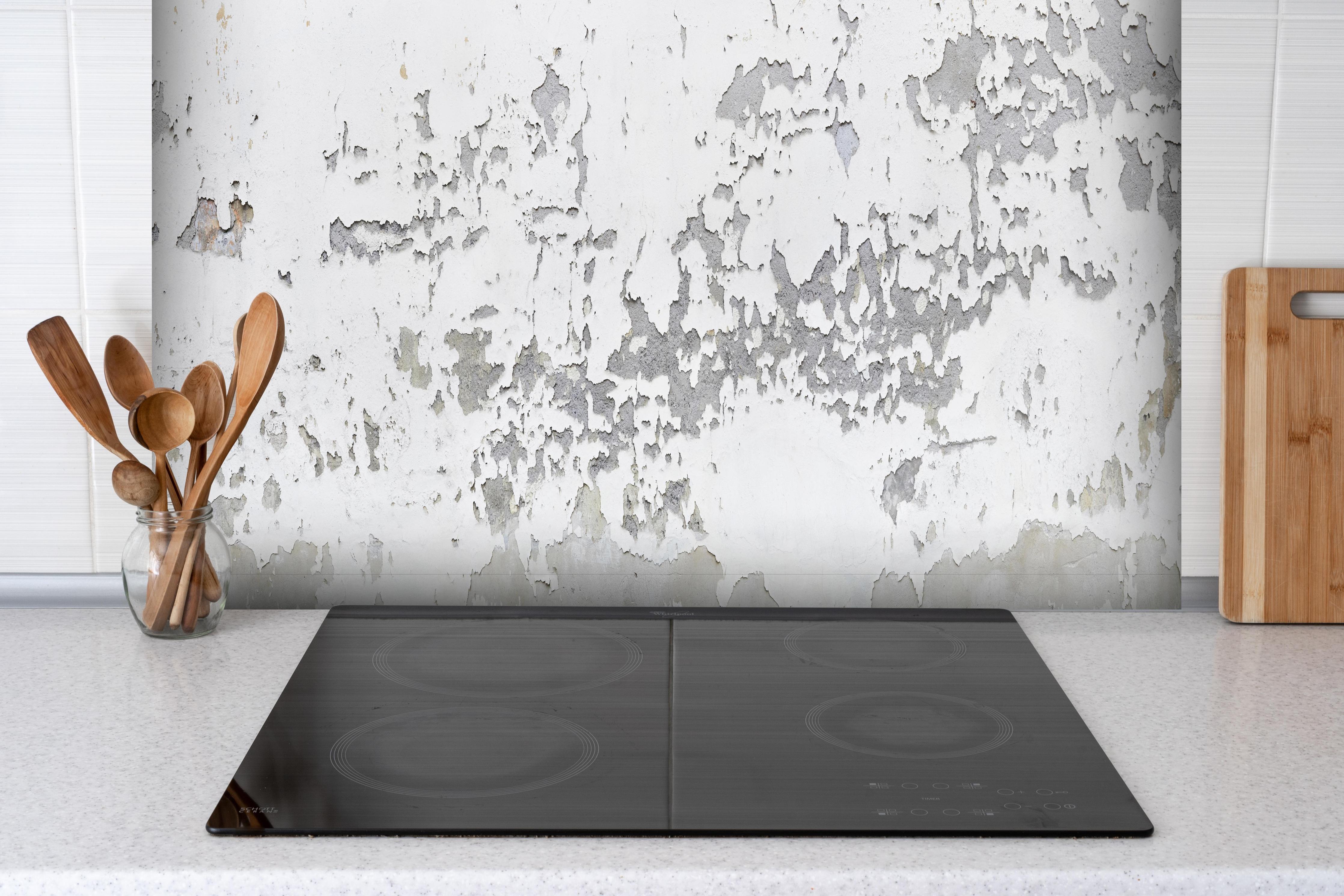 Spritzschutz - Beschädigte Wandstruktur hinter einem Cerankochfeld zwischen Holz-Kochutensilien