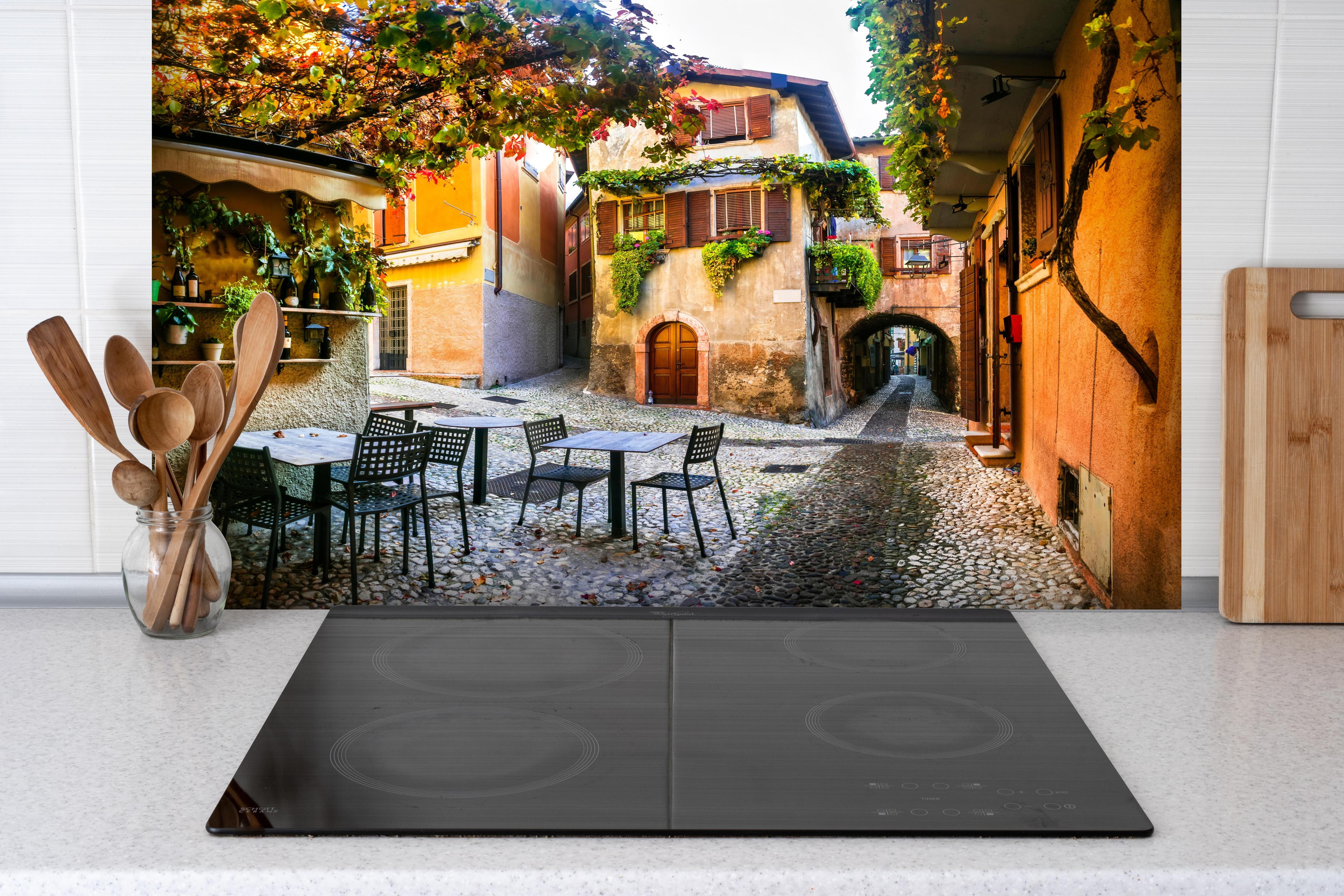 Spritzschutz - Bezaubernde alte Gasse in Malcesine hinter einem Cerankochfeld zwischen Holz-Kochutensilien