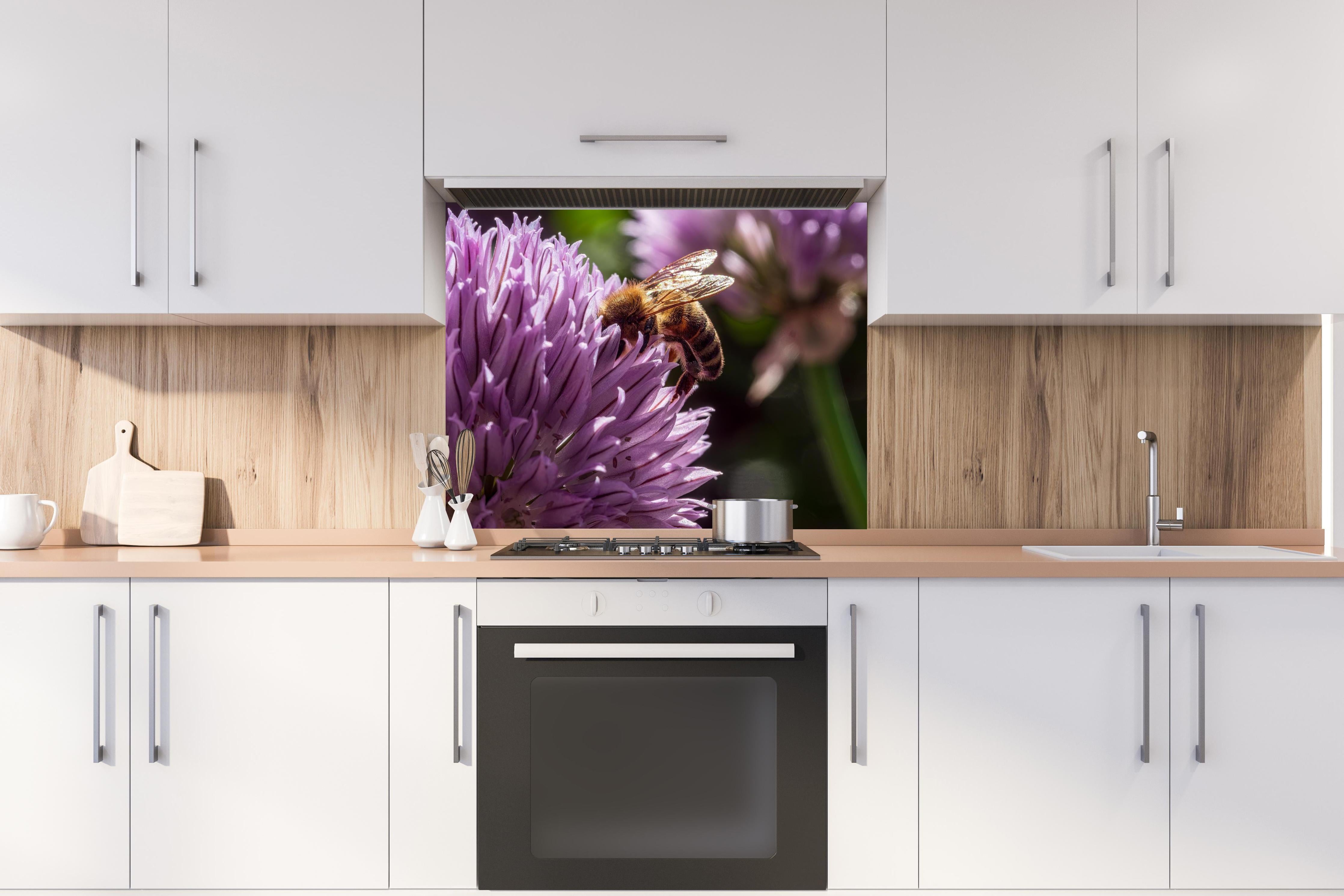 Spritzschutz - Biene auf lila Blüte Makroaufnahme hinter einem Cerankochfeld zwischen Holz-Kochutensilien