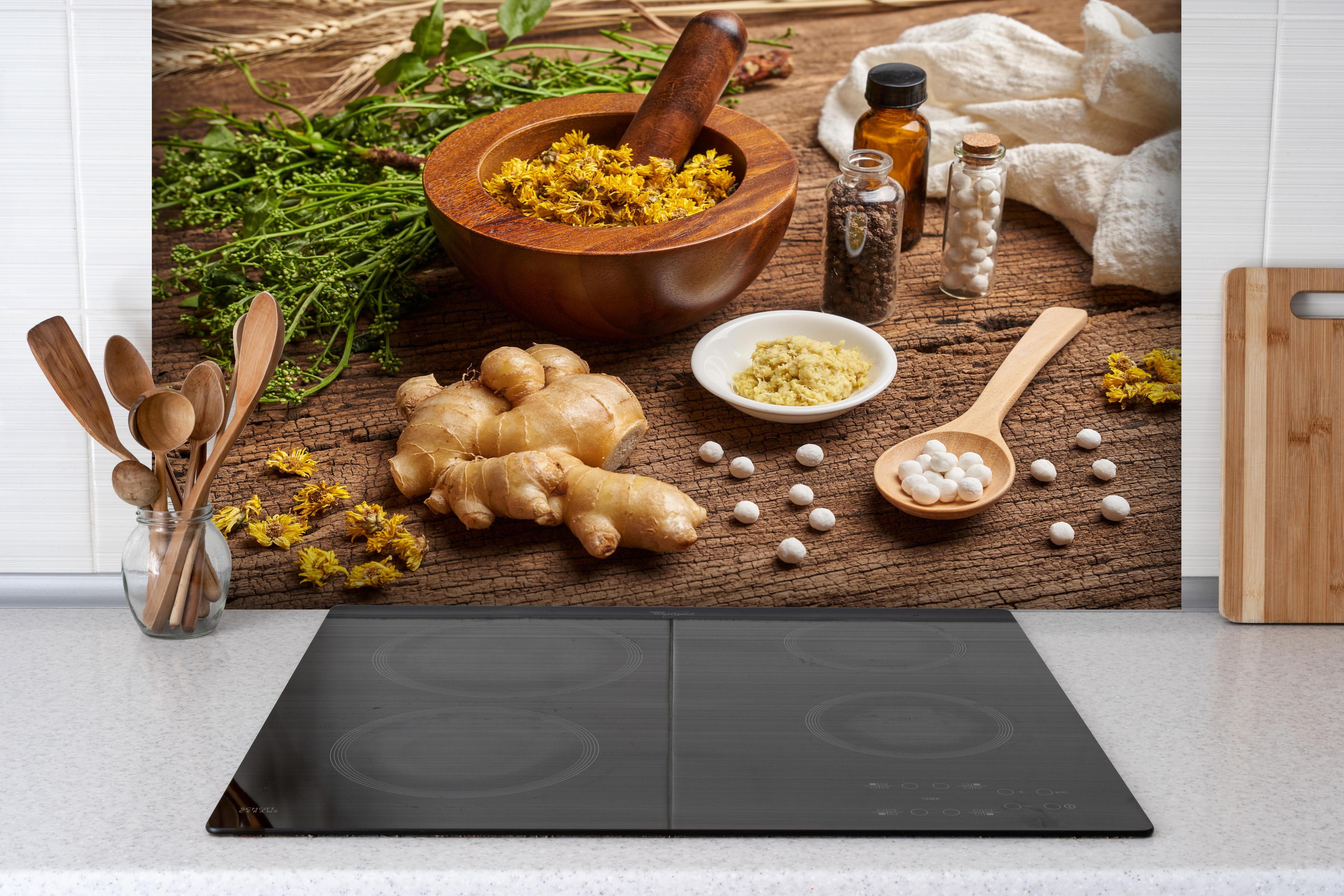 Spritzschutz - Bio Heilkräuter und Naturheilmittel Wellness hinter einem Cerankochfeld zwischen Holz-Kochutensilien