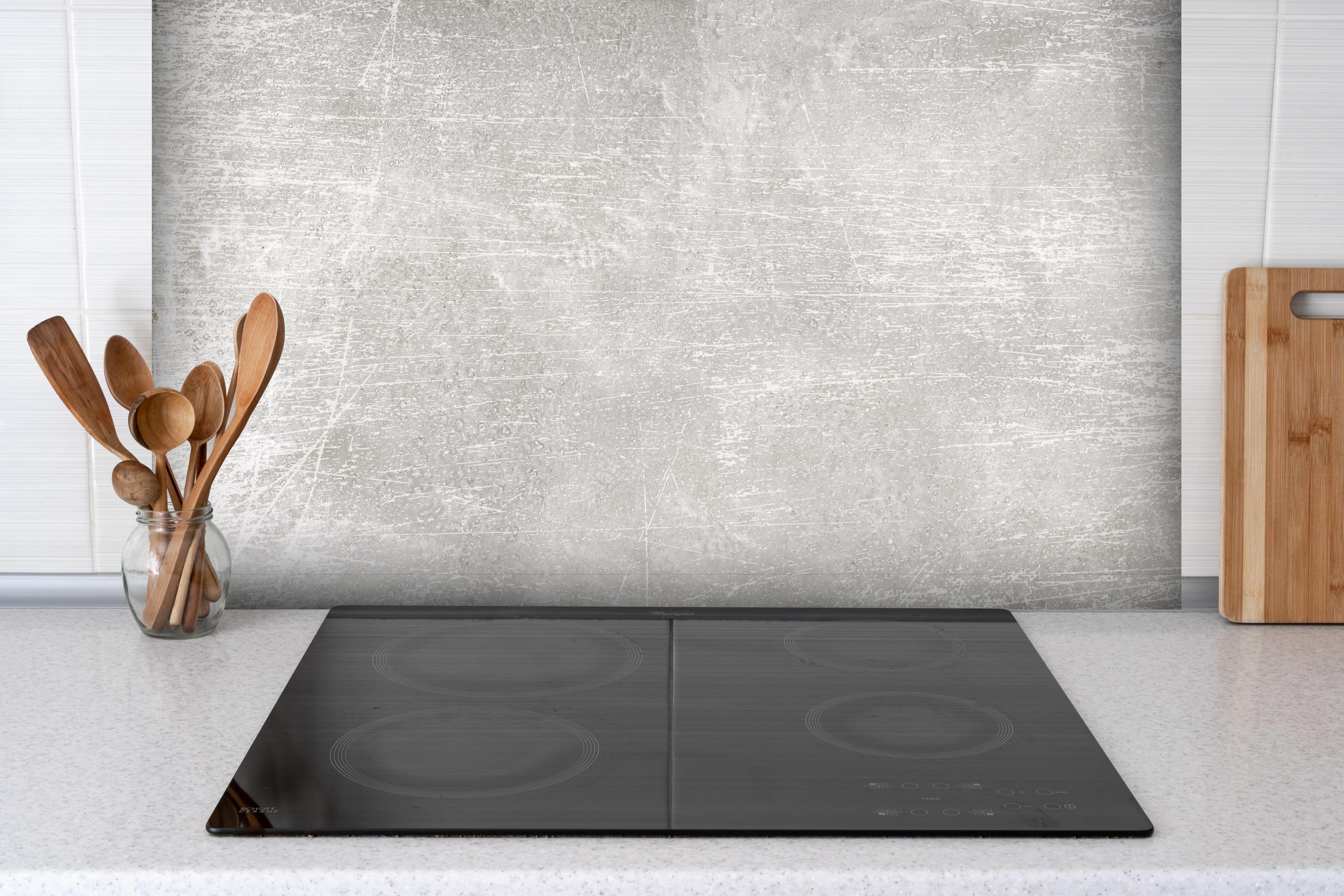 Spritzschutz - Blanker Zement Hintergrund hinter einem Cerankochfeld zwischen Holz-Kochutensilien