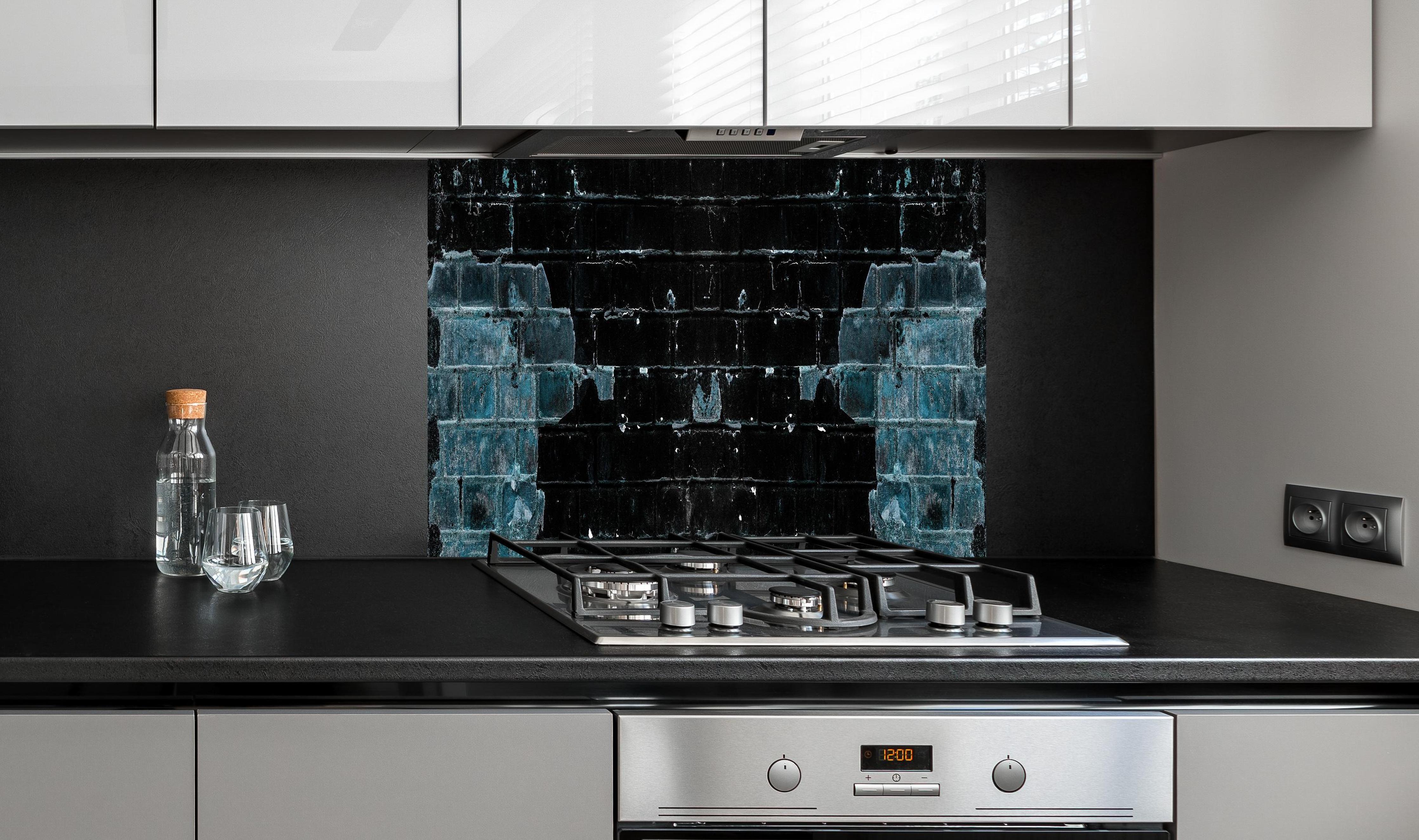 Spritzschutz - Blau schwarz beschädigte Ziegelwand hinter einem Cerankochfeld zwischen Holz-Kochutensilien