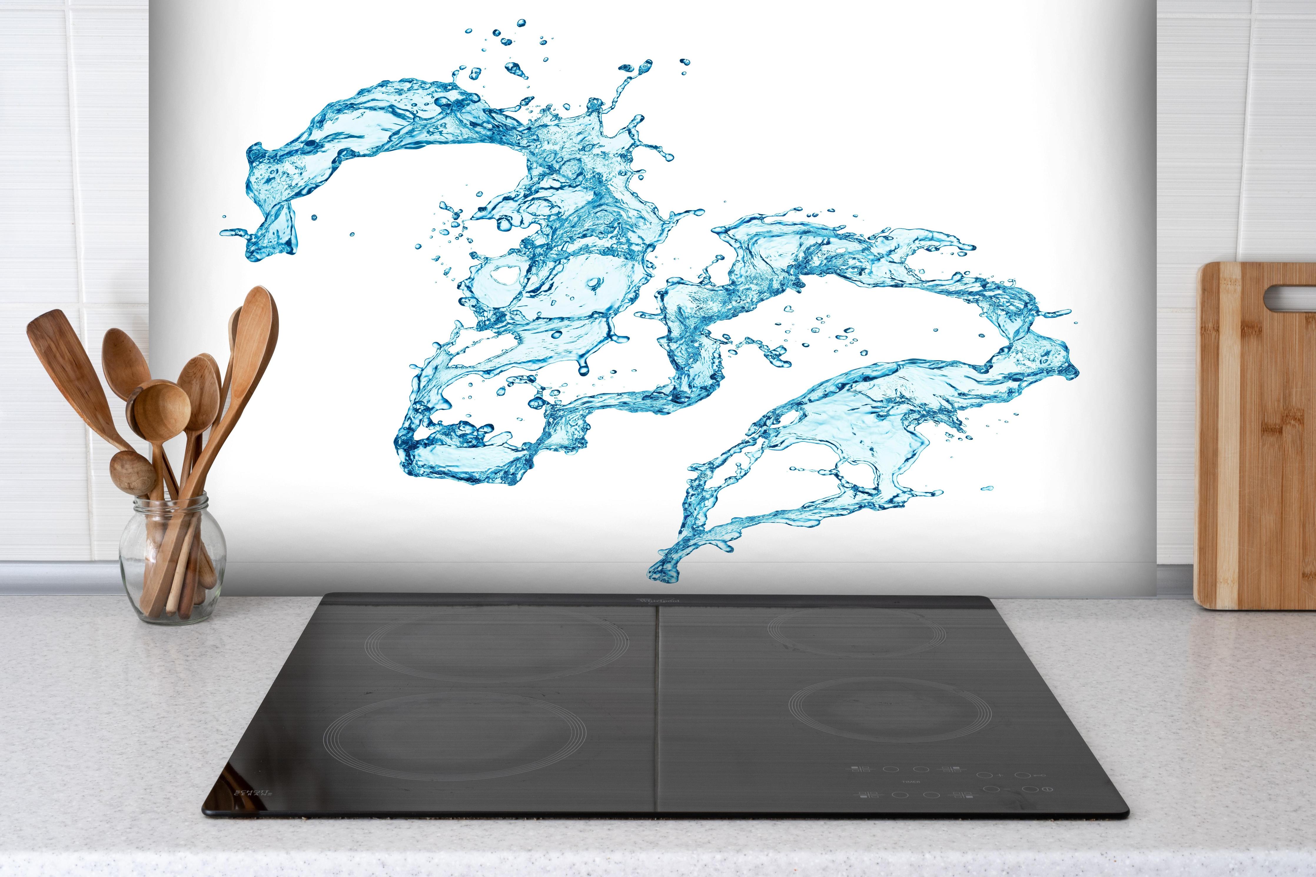 Spritzschutz - Blaue Wasser Spritzer weißer Hintergrund hinter einem Cerankochfeld zwischen Holz-Kochutensilien