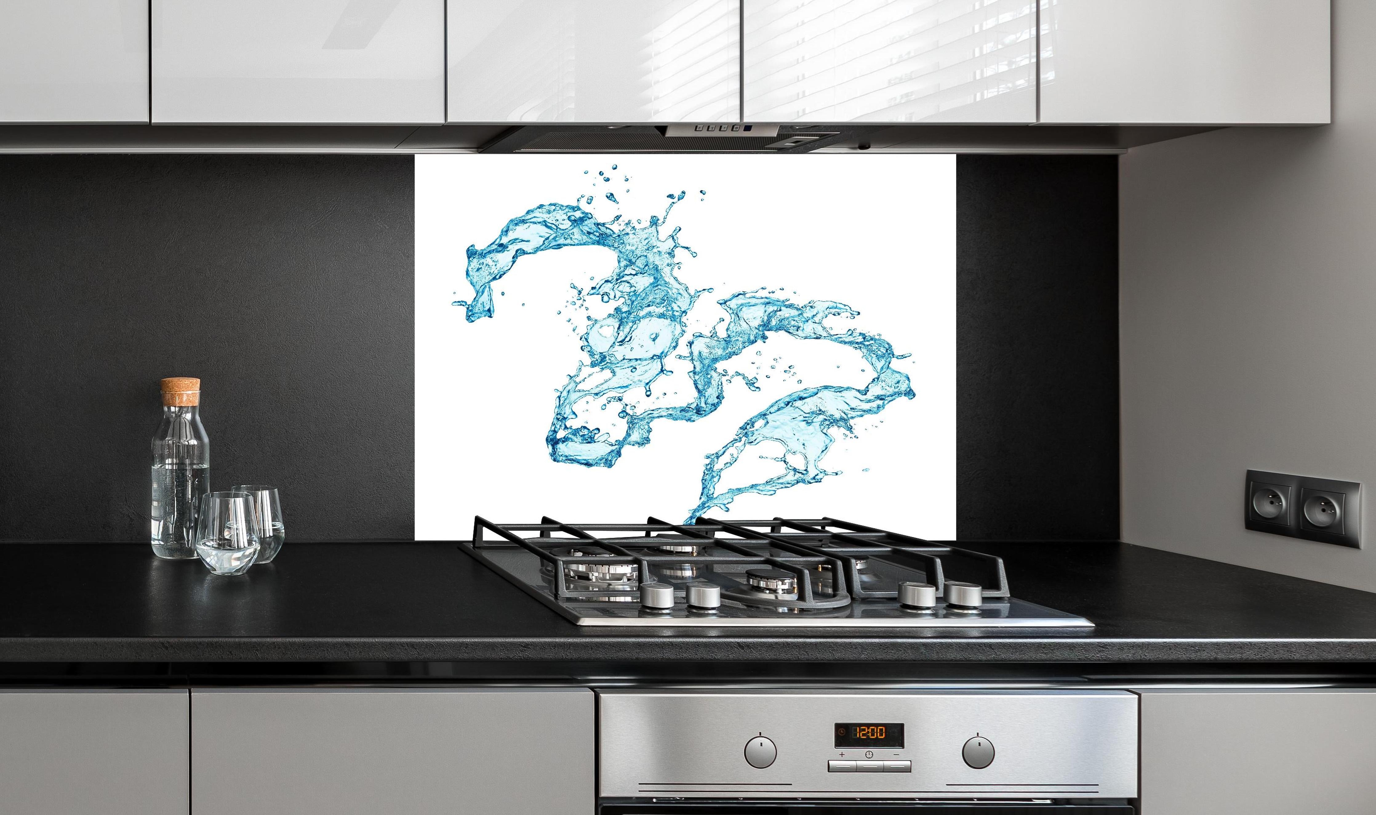 Spritzschutz - Blaue Wasser Spritzer weißer Hintergrund hinter einem Cerankochfeld zwischen Holz-Kochutensilien