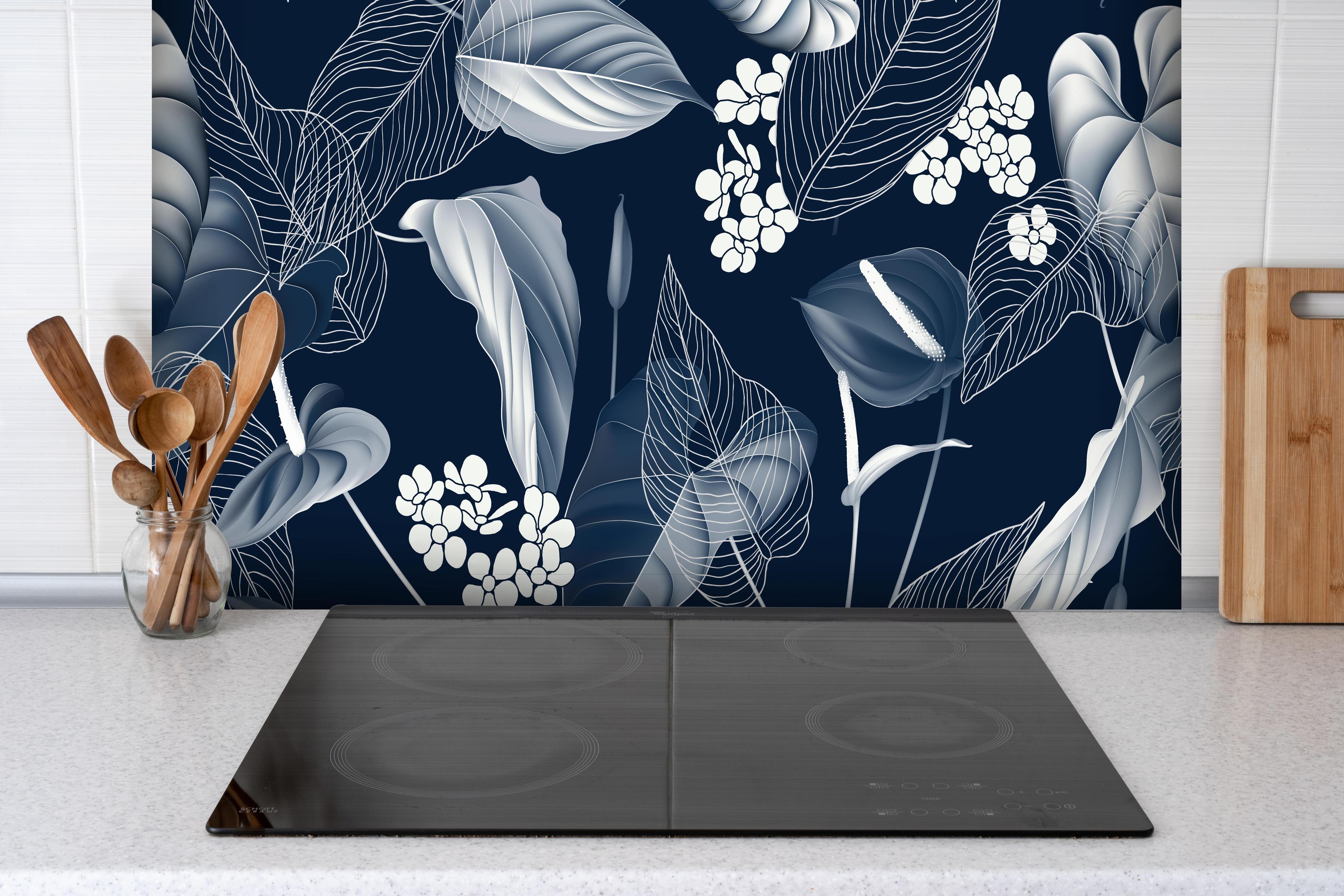 Spritzschutz - Blaue tropische Pflanzen hinter einem Cerankochfeld zwischen Holz-Kochutensilien