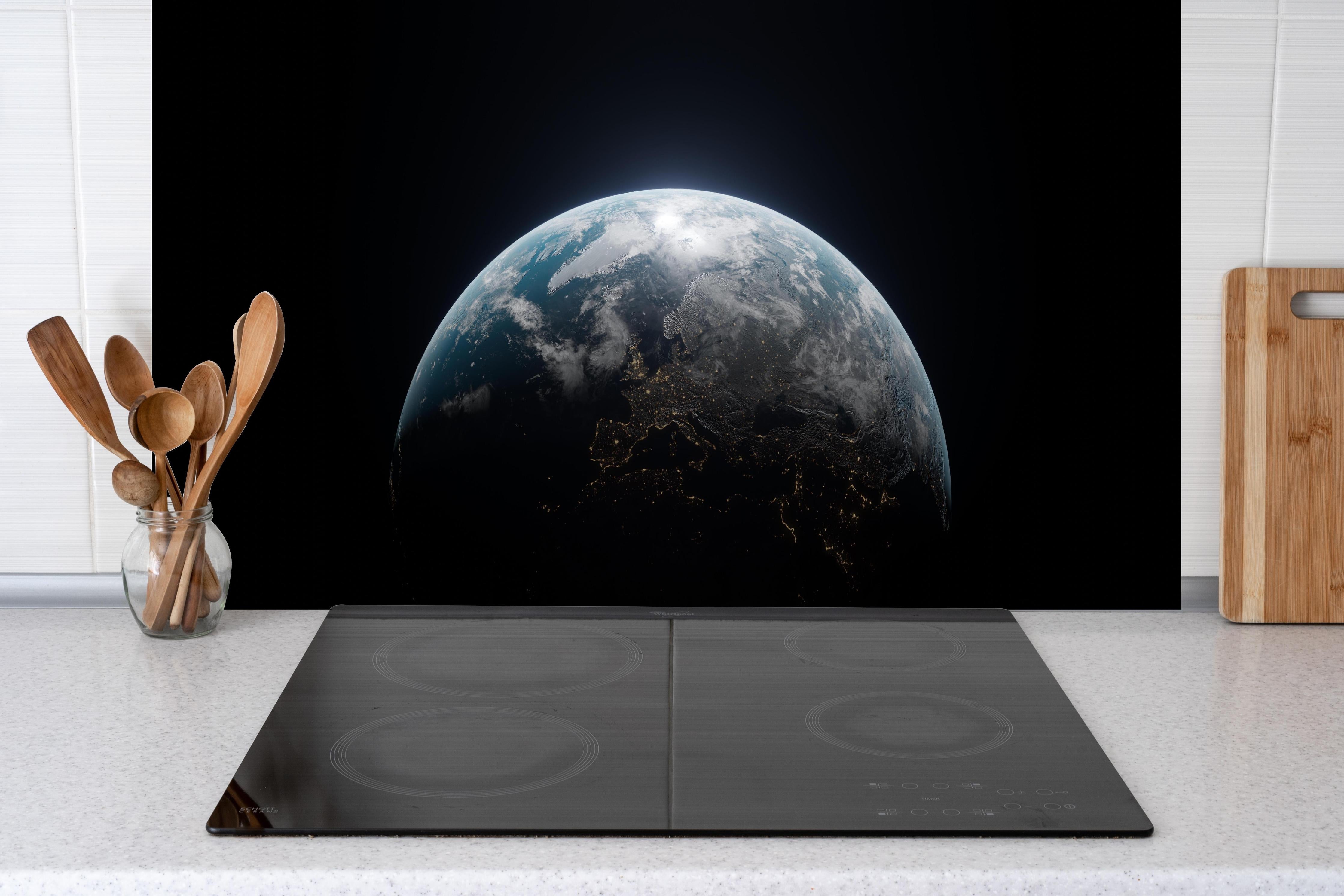 Spritzschutz - Blick auf die Erde hinter einem Cerankochfeld zwischen Holz-Kochutensilien