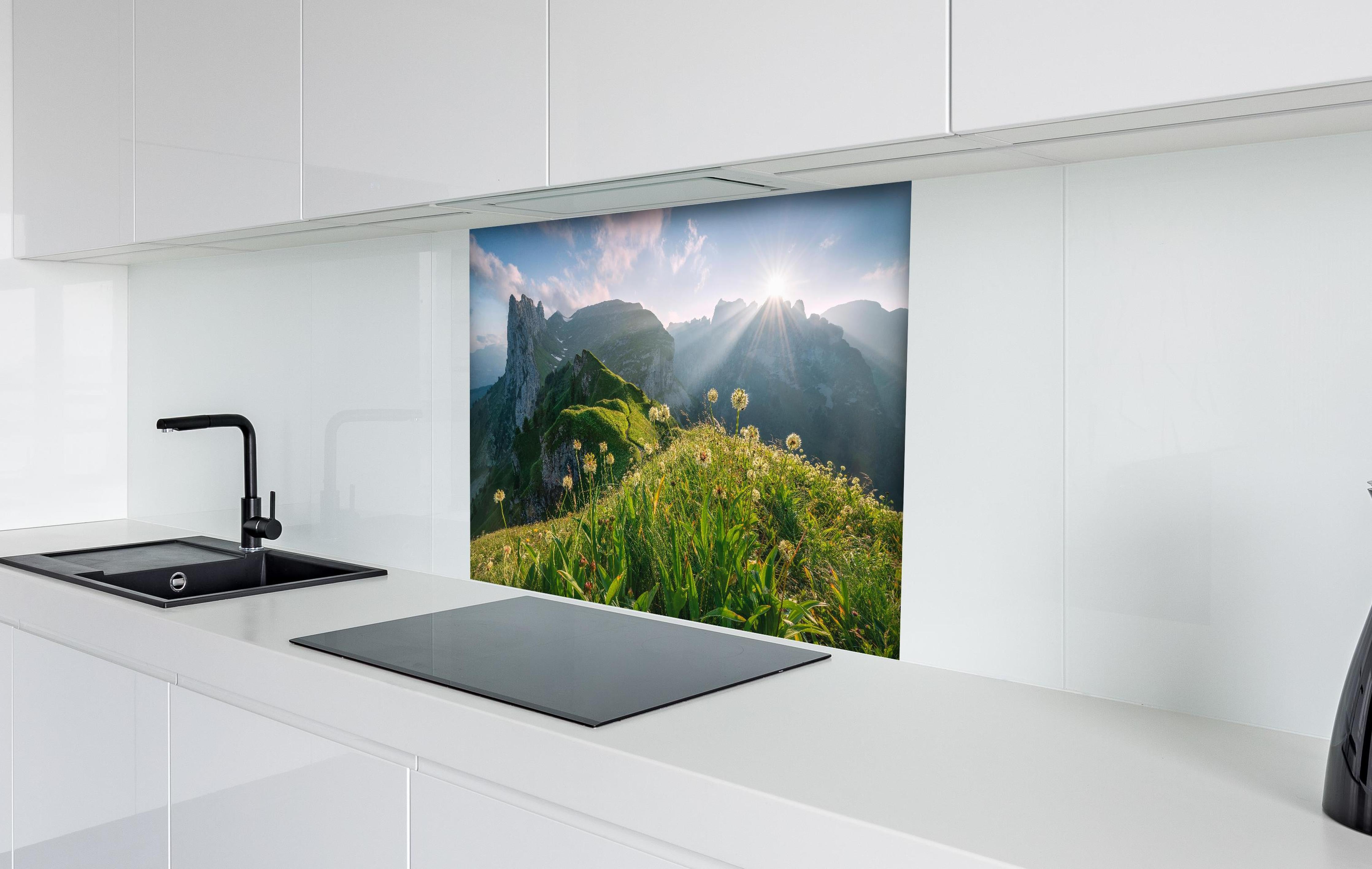 Spritzschutz - Blühende Alpenwiesen bei Sonnenaufgang hinter einem Cerankochfeld zwischen Holz-Kochutensilien