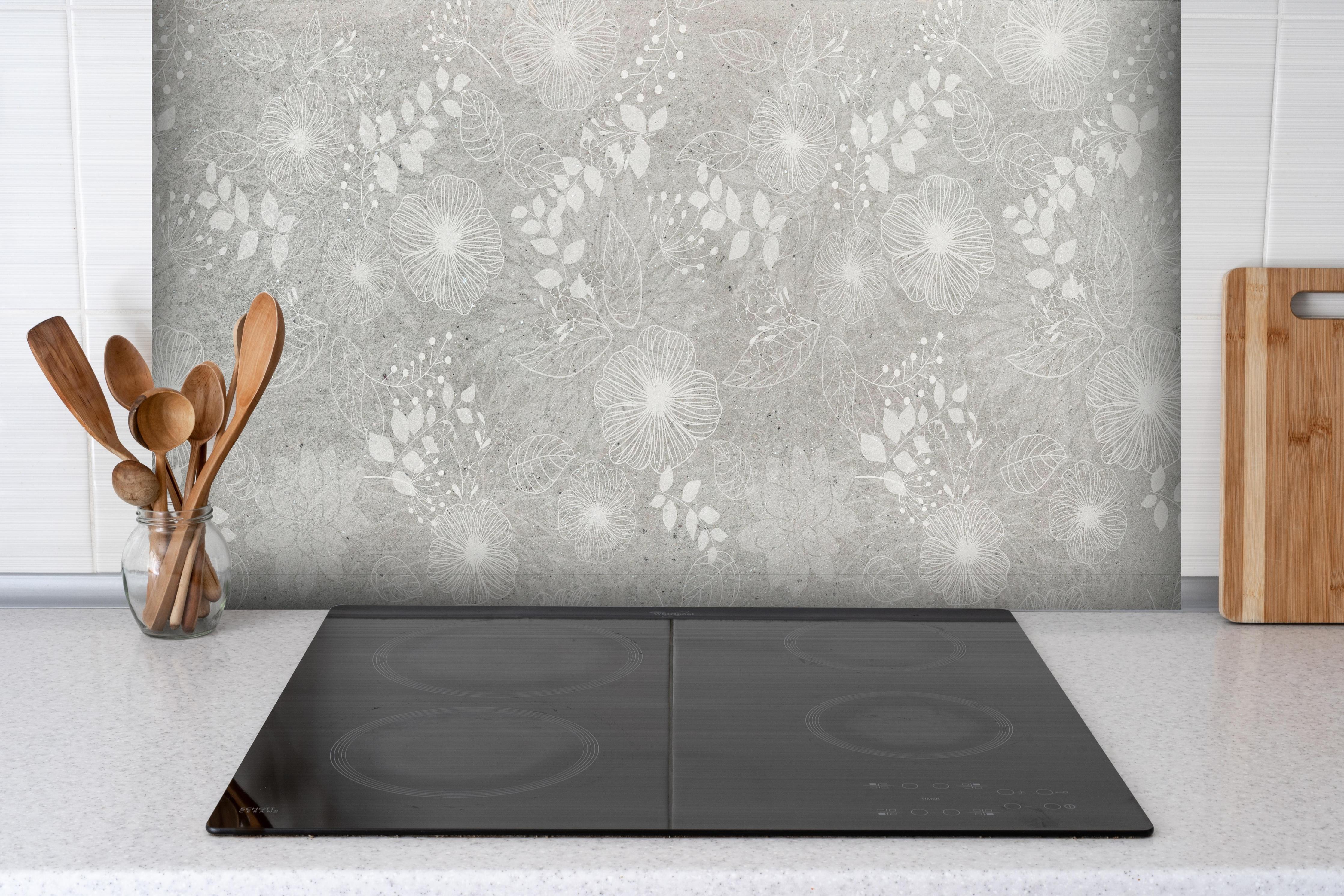 Spritzschutz - Blumen auf grauem Beton hinter einem Cerankochfeld zwischen Holz-Kochutensilien