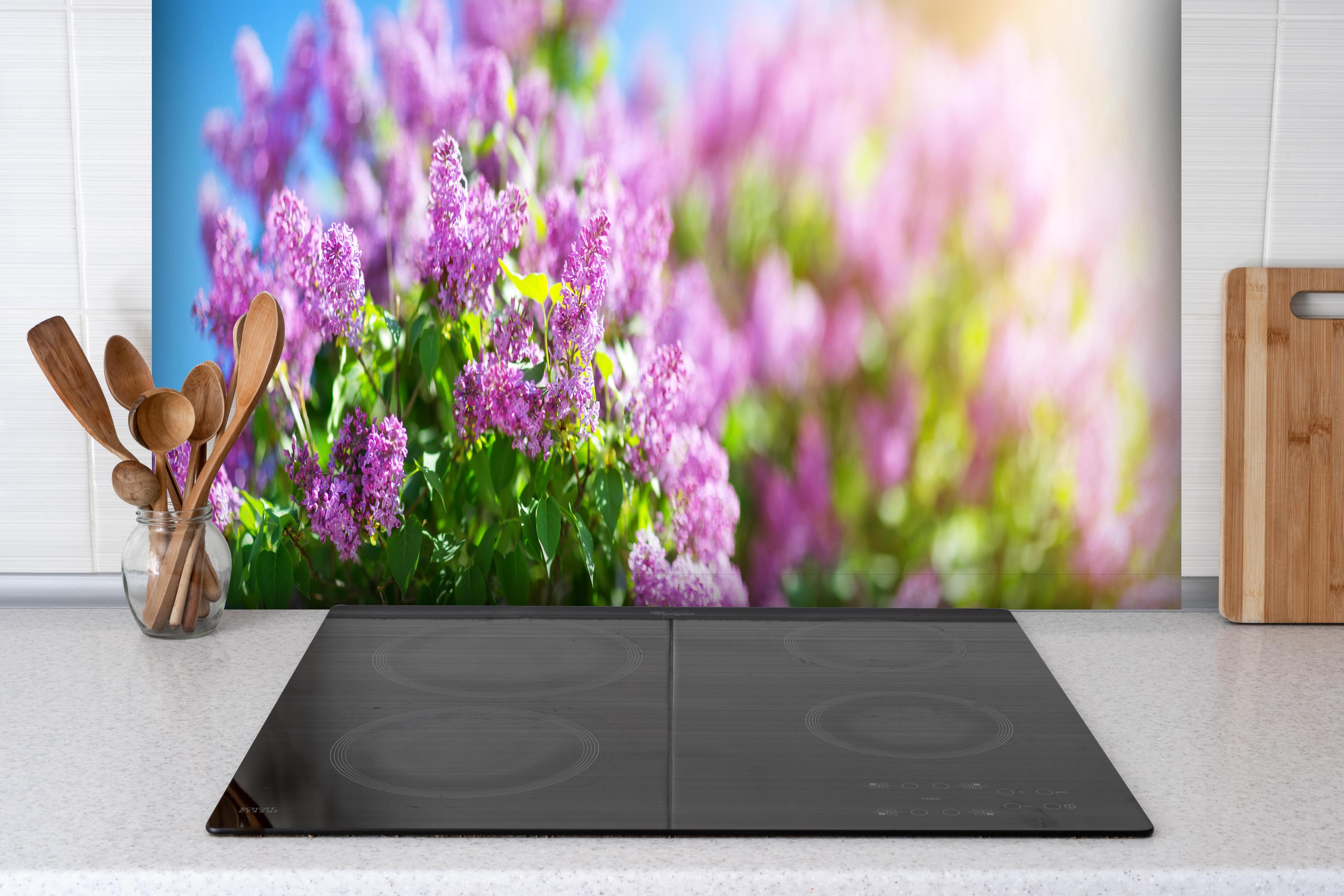 Spritzschutz - Blumen blühen auf im Frühling hinter einem Cerankochfeld zwischen Holz-Kochutensilien