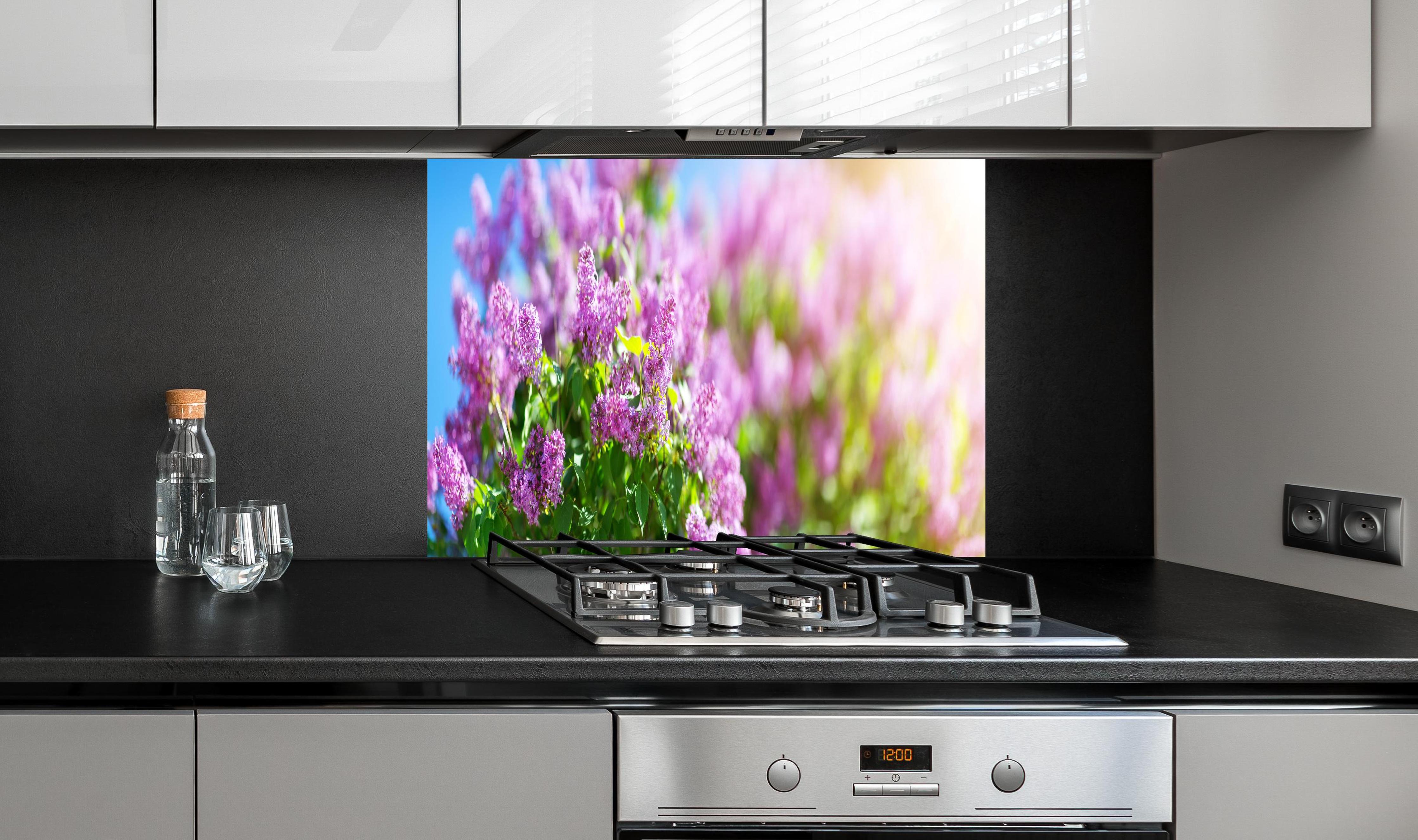 Spritzschutz - Blumen blühen auf im Frühling hinter einem Cerankochfeld zwischen Holz-Kochutensilien