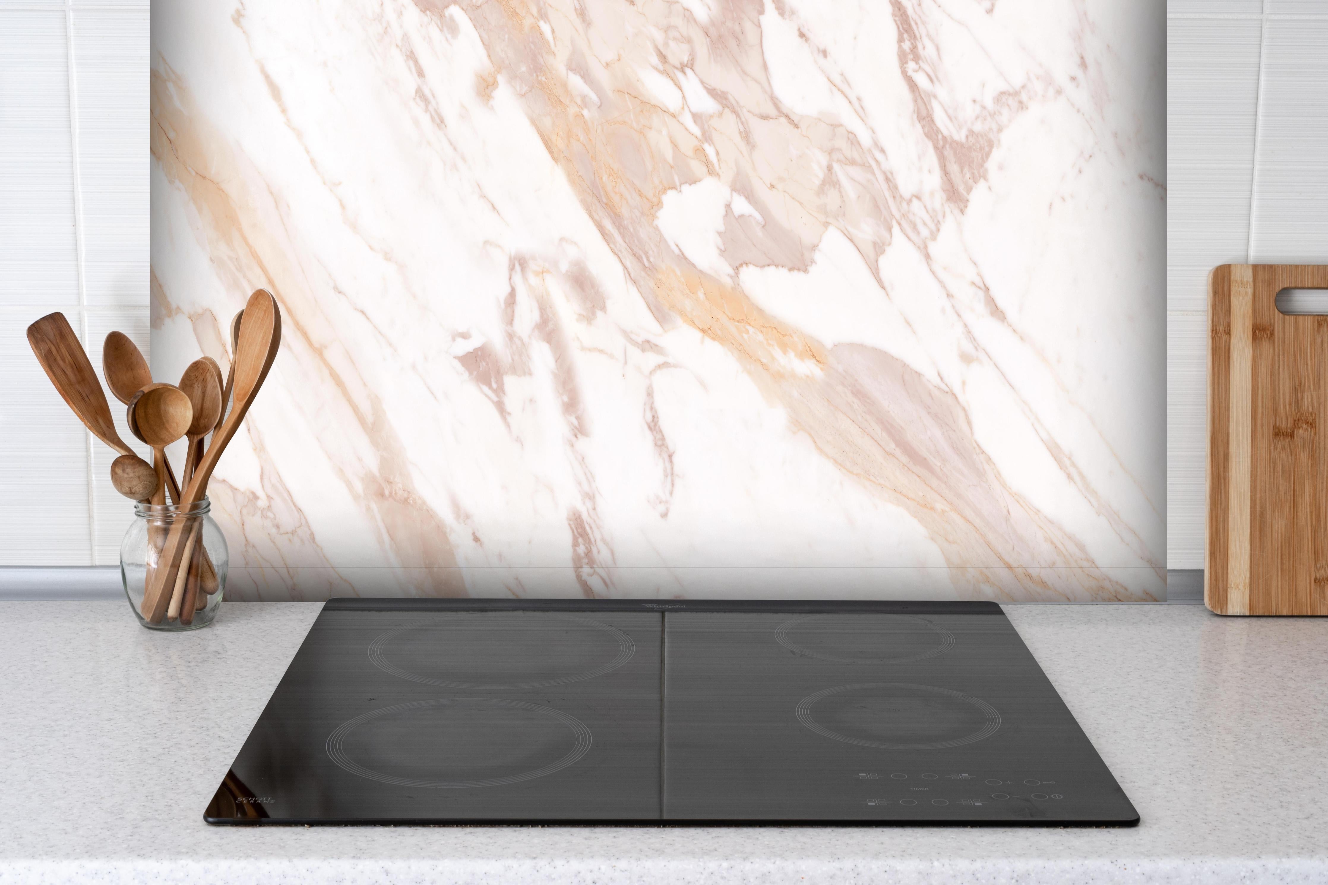 Spritzschutz - Braun-beiger Marmor hinter einem Cerankochfeld zwischen Holz-Kochutensilien