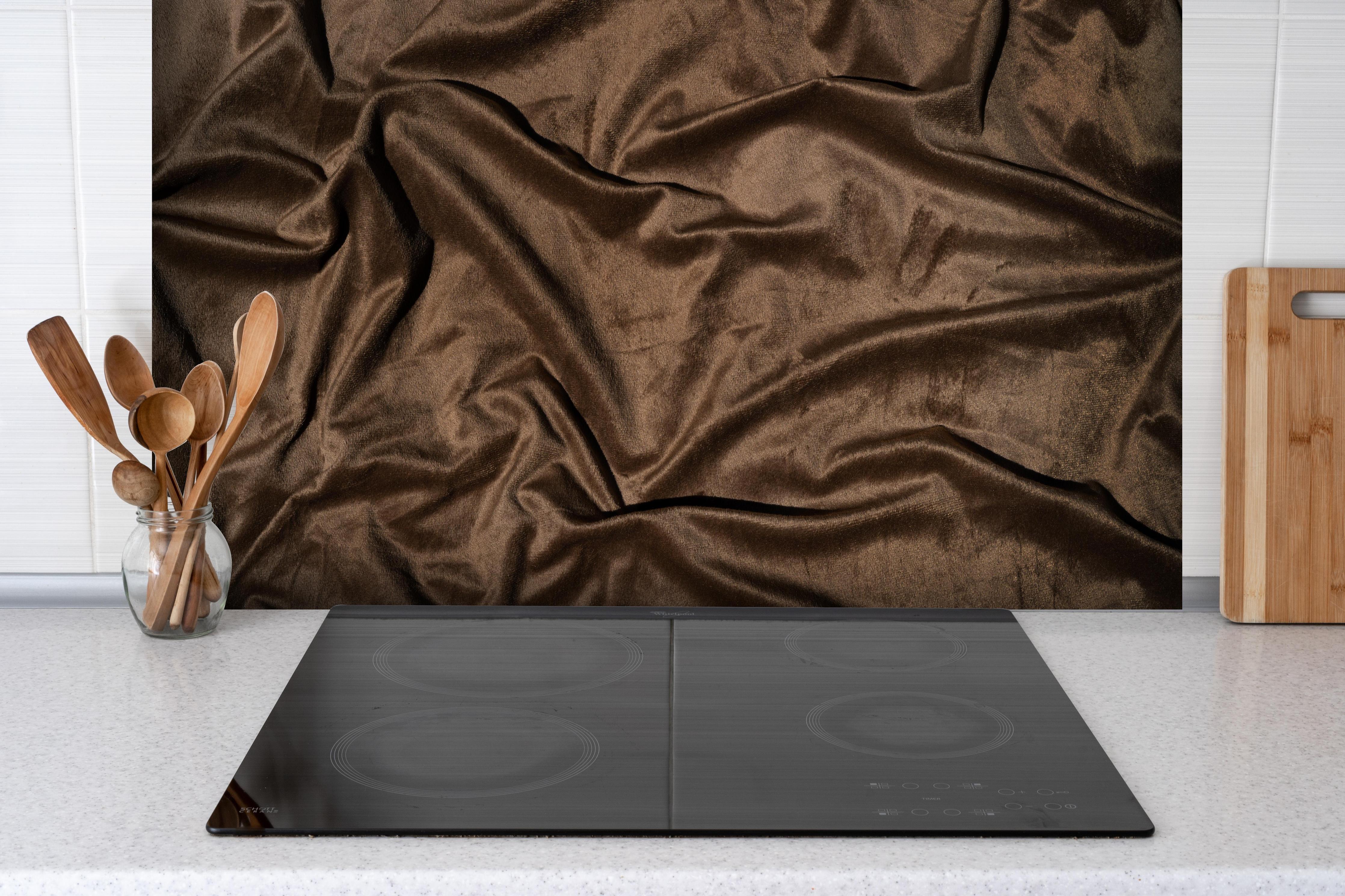 Spritzschutz - Braune Satin Seide hinter einem Cerankochfeld zwischen Holz-Kochutensilien